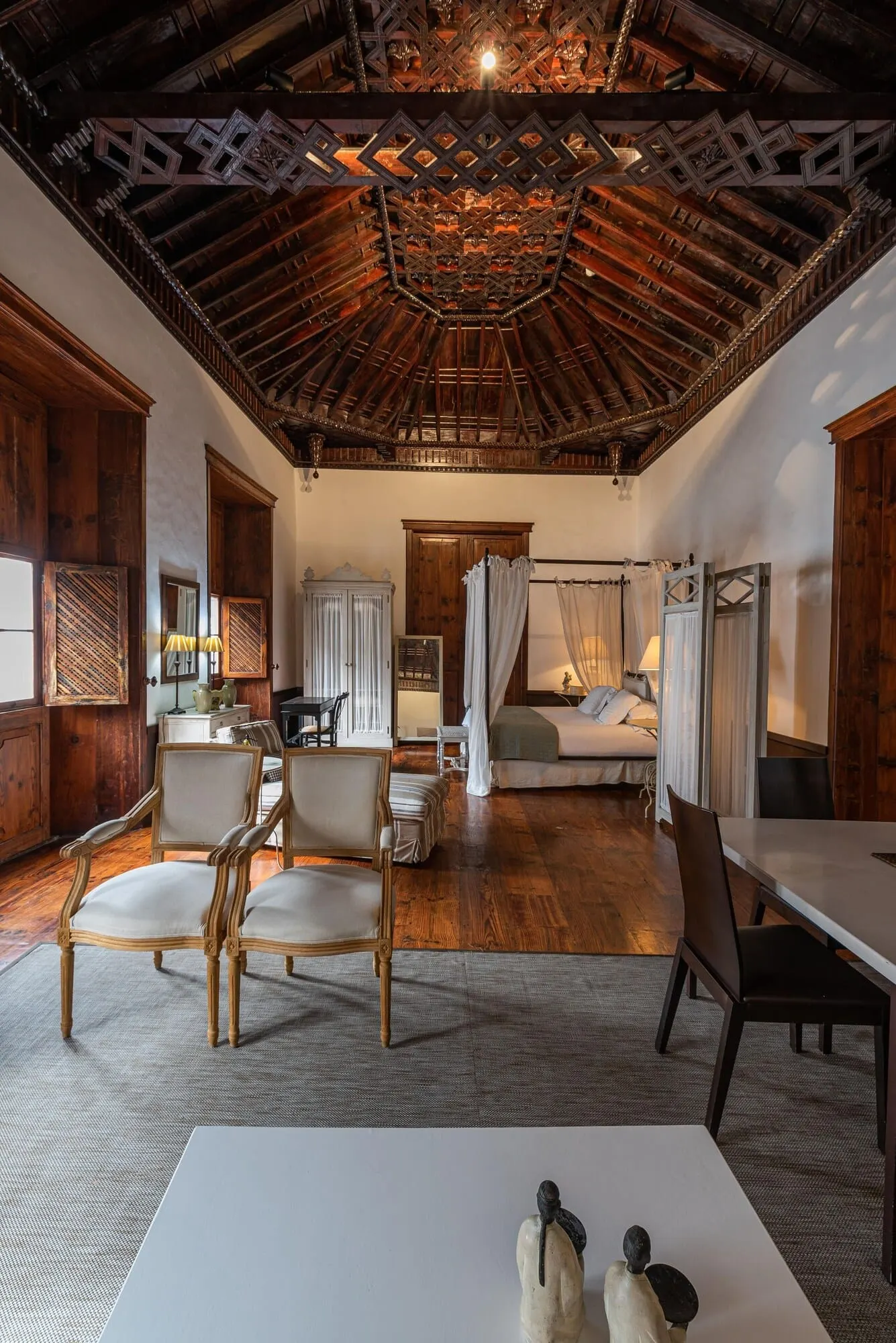 Isla Baja Suites: A room with a wooden ceiling, a bed with a canopy, a dining table, and chairs