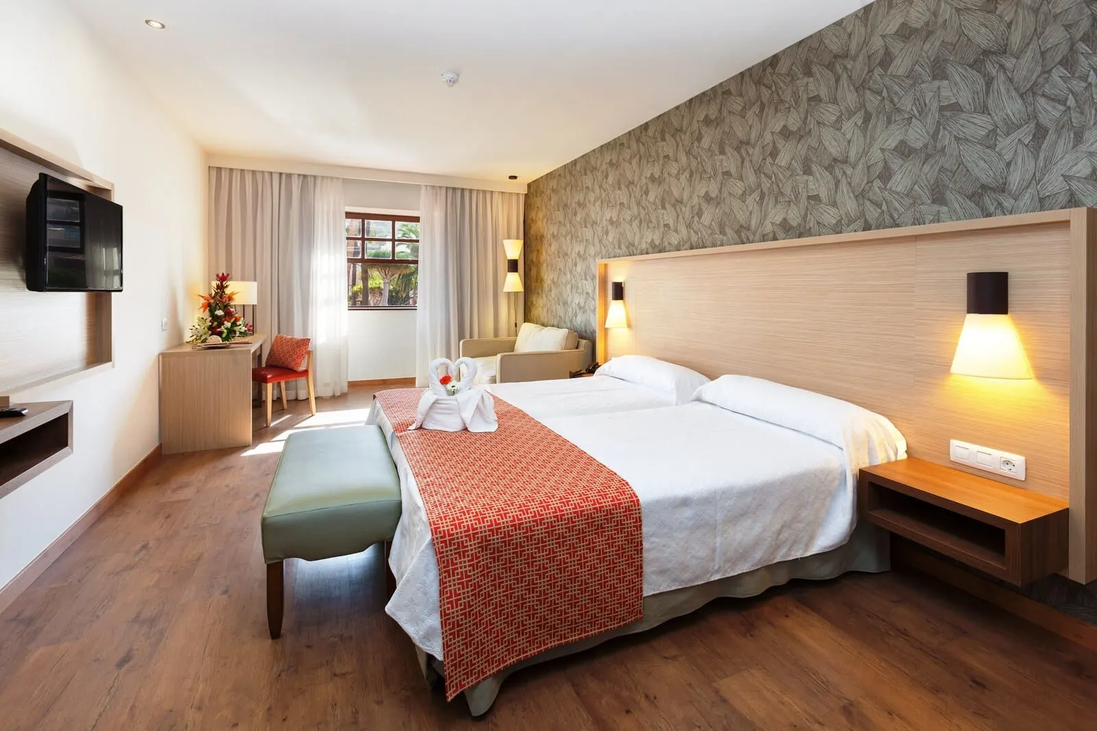 Marquesa Hotel: A hotel room with a large bed, a desk, a chair, a TV, and a window with curtains