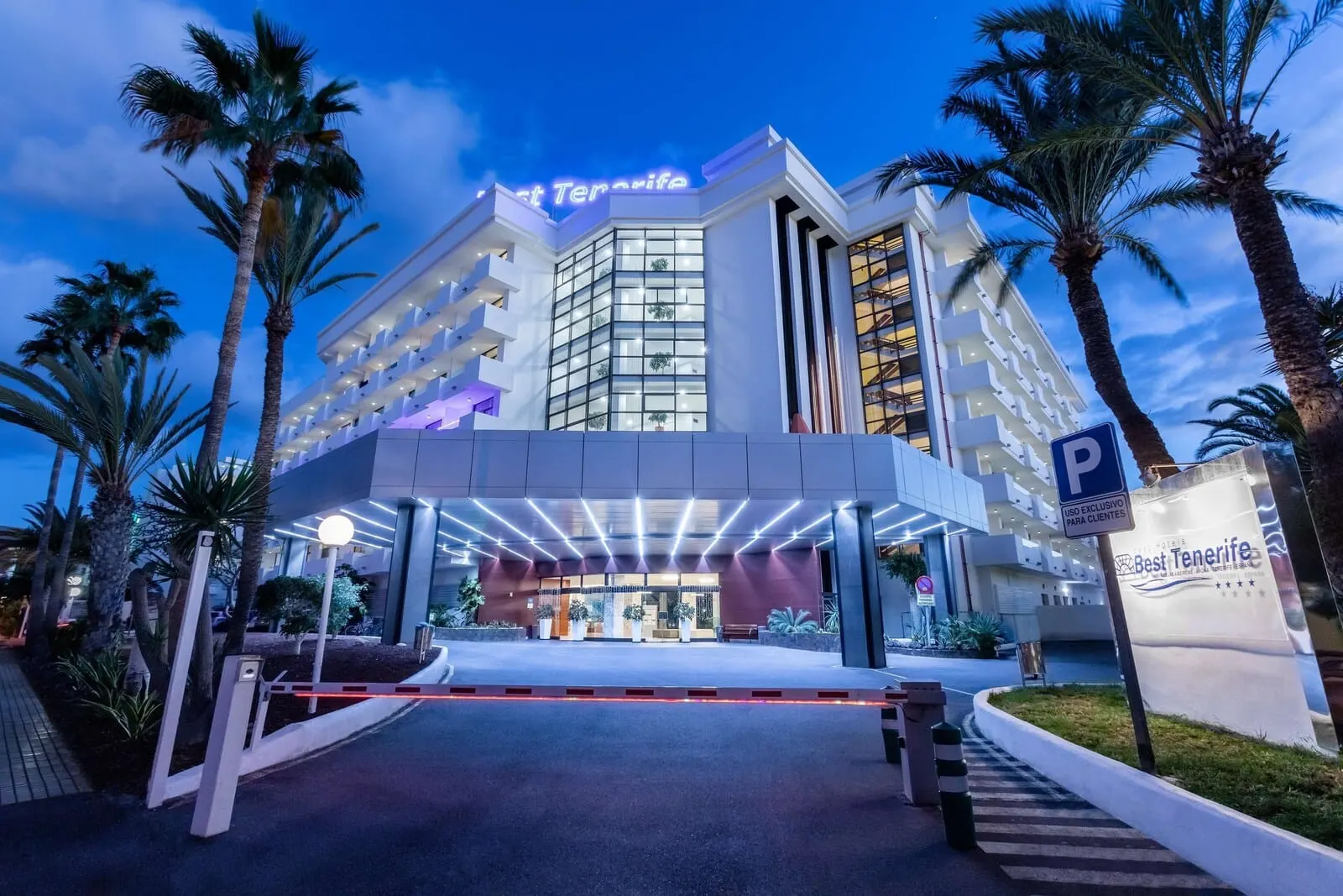 Best Tenerife: A hotel entrance with a modern design, palm trees, and a clear sky