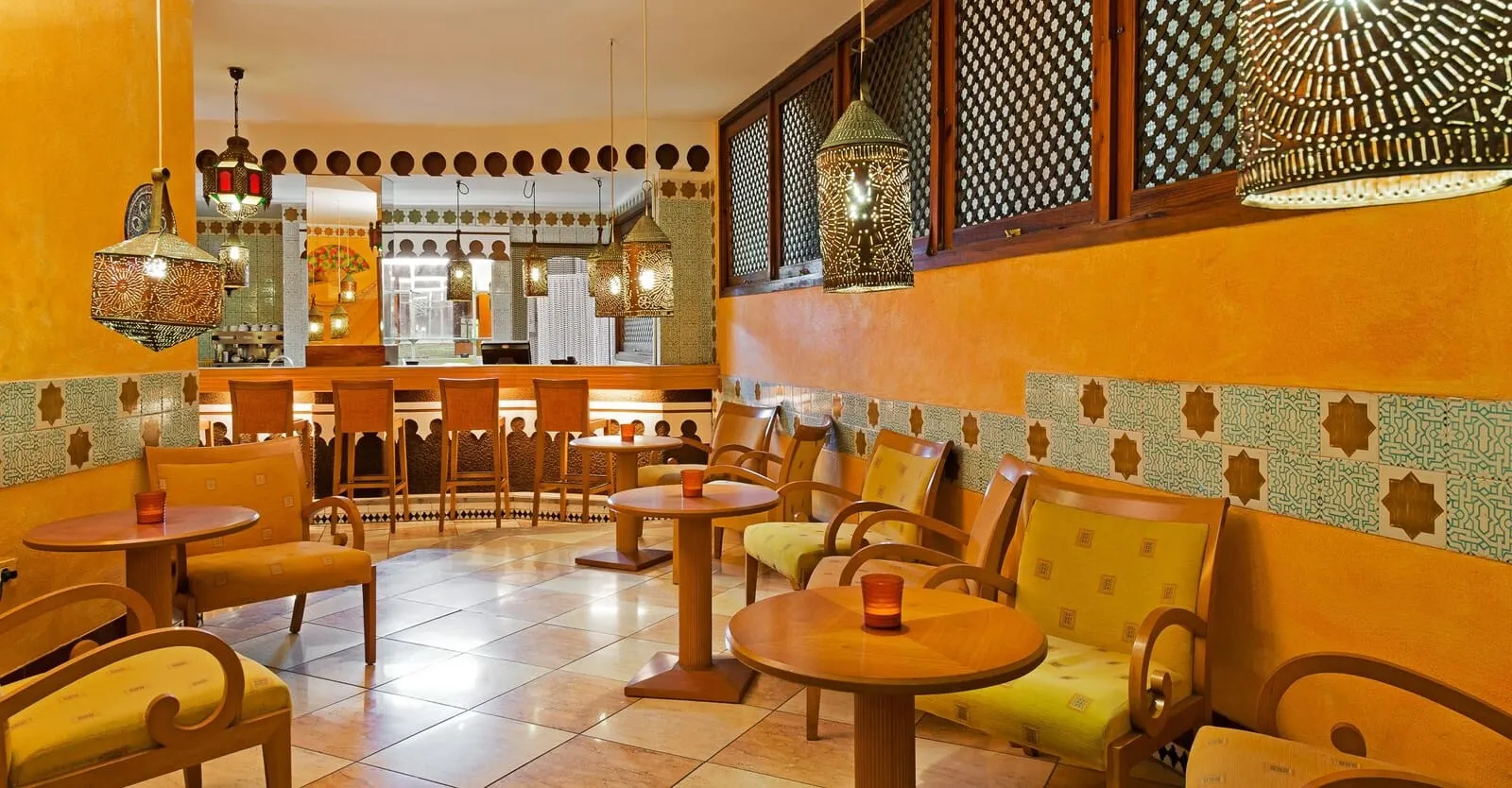 Hotel Monopol: A cozy restaurant interior with patterned walls, wooden furniture, and hanging lanterns