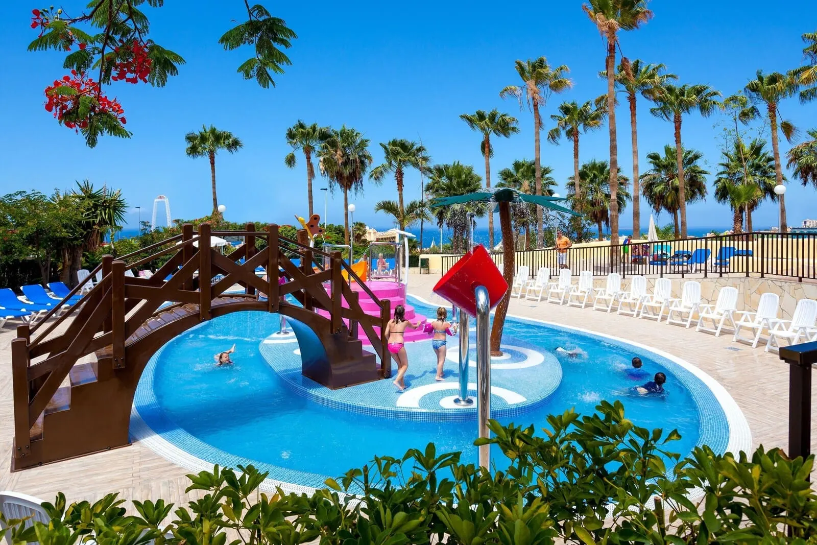 Tagoro Family & Fun Costa Adeje: A swimming pool with a wooden bridge, palm trees, and lounge chairs