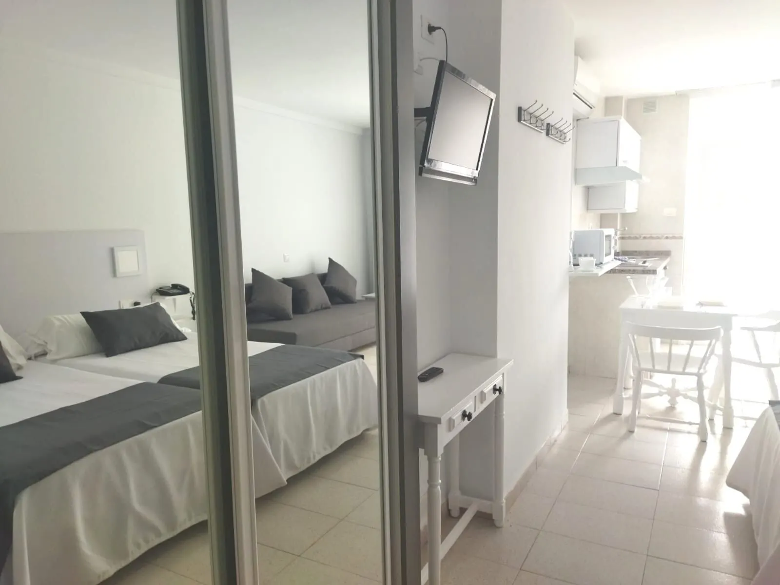 Apartamentos Pez Azul: A hotel room with two beds, a TV, a desk, and a kitchenette