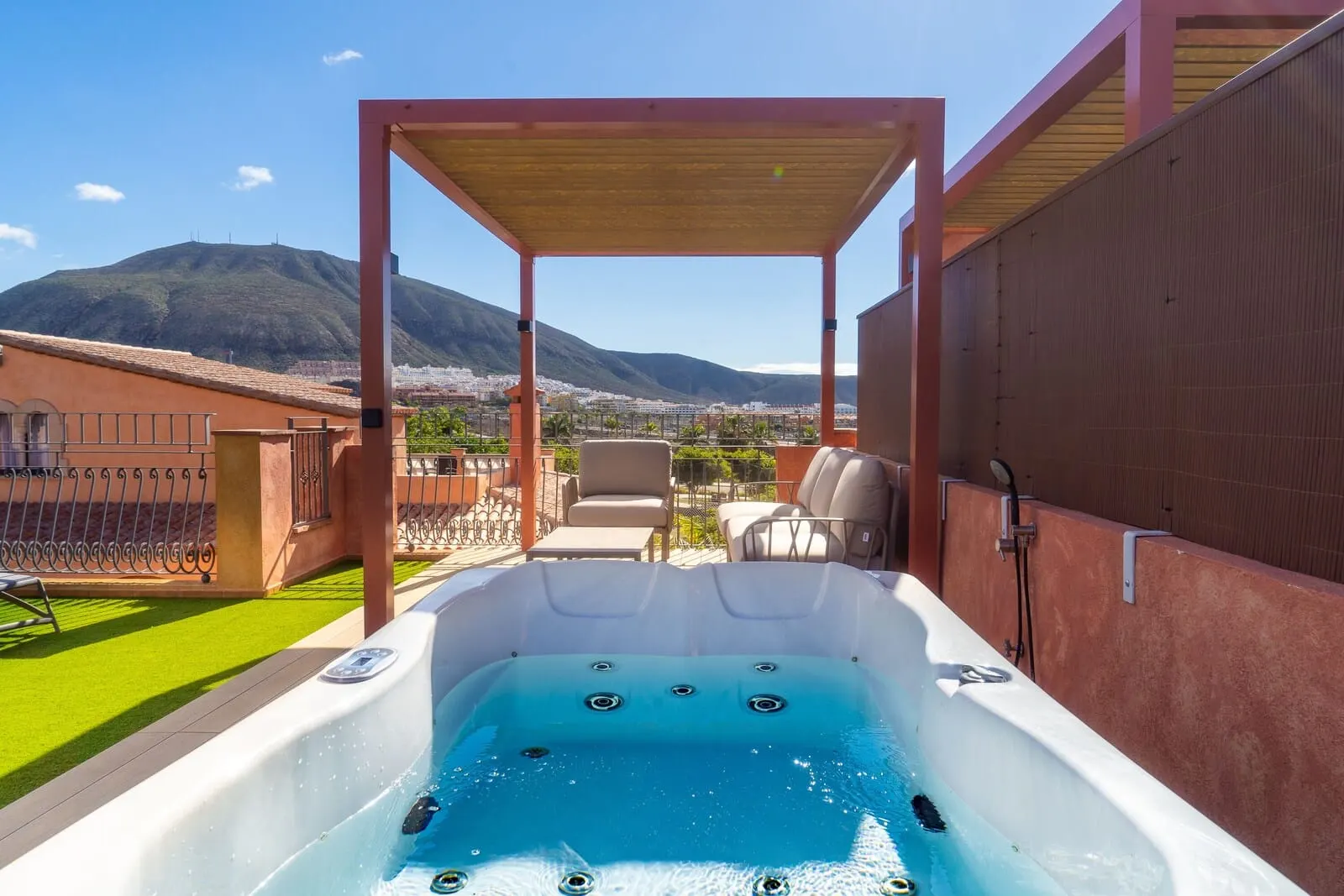 Villa Mandi Golf Resort: A hot tub with a mountain view, outdoor seating, and a pergola structure