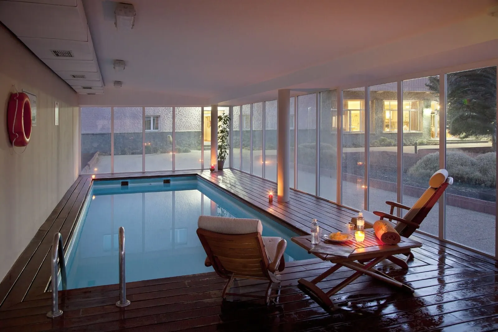 Parador de Las Cañadas del Teide: A swimming pool with wooden deck seating and a view of the outside