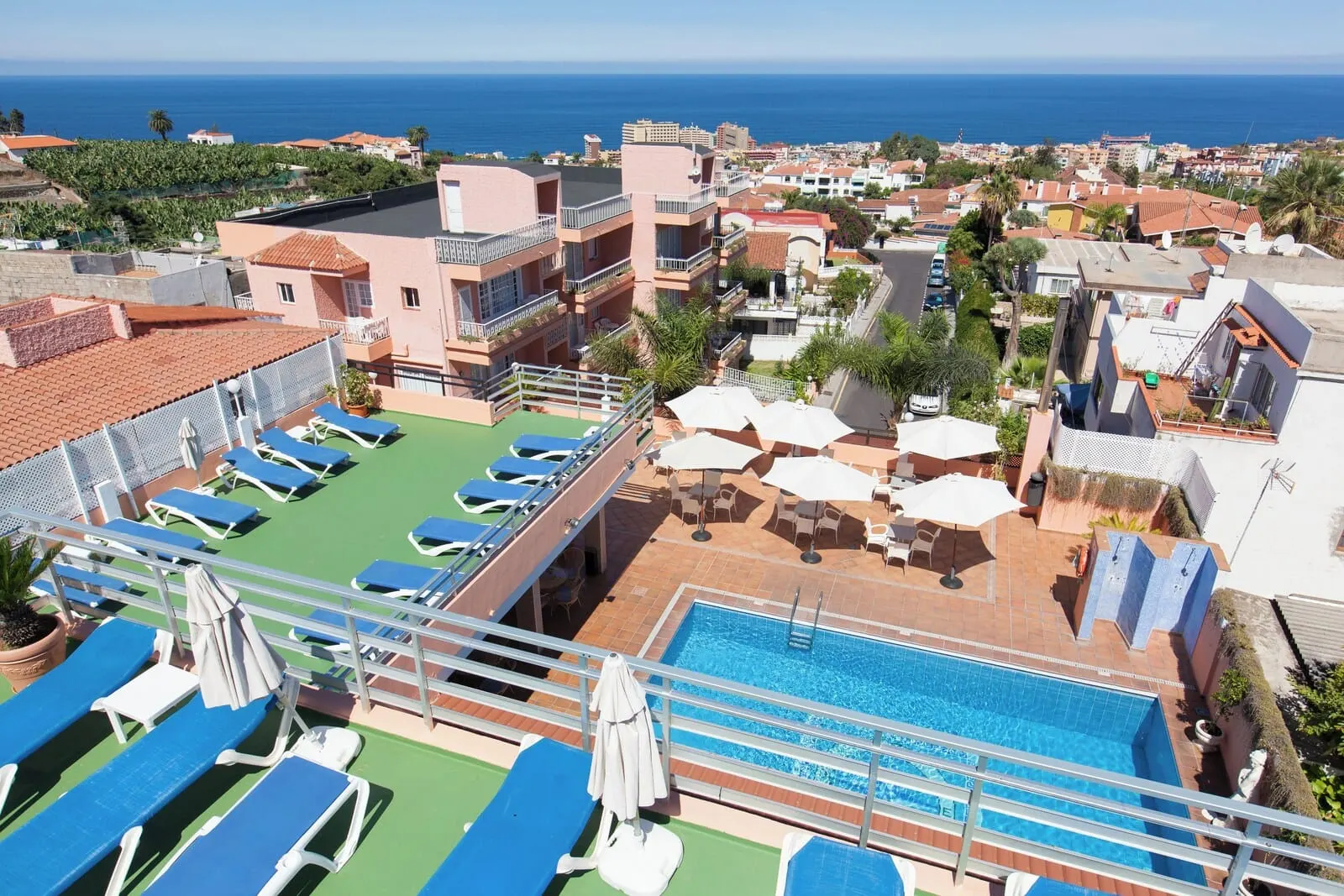Globales Acuario: A rooftop pool area with lounge chairs and umbrellas, overlooking a coastal cityscape