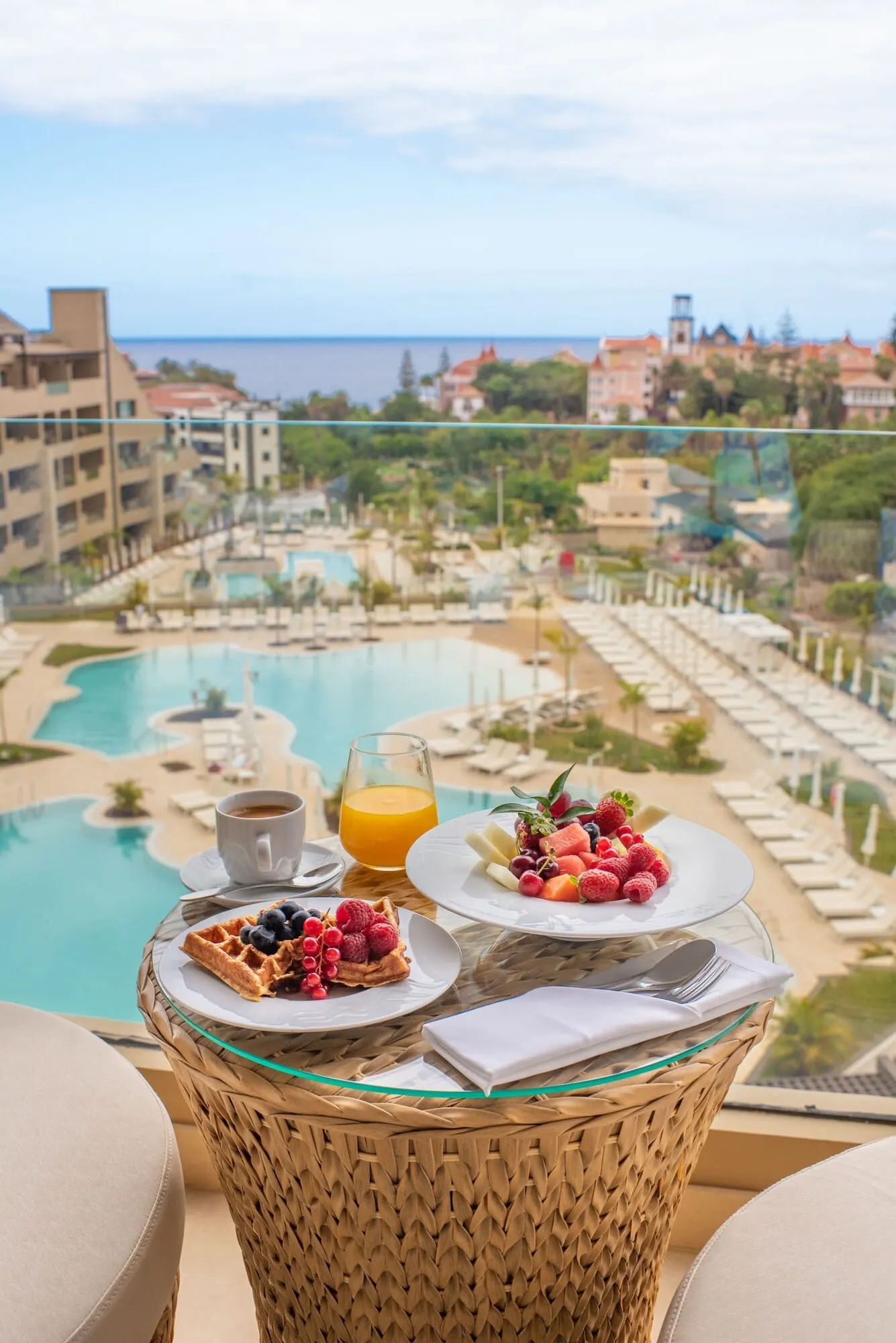 GF Victoria: A balcony with a wicker table set for breakfast, overlooking a pool and resort area