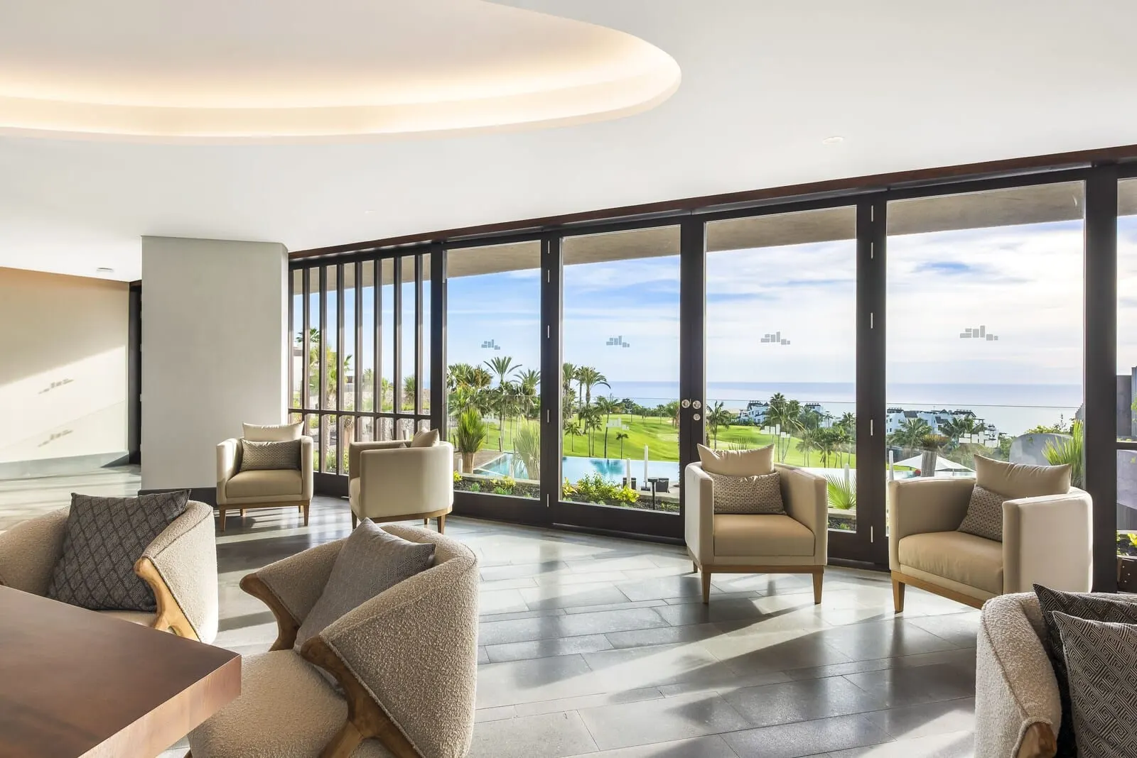 Los Jardines de Abama Suites & Villas: A spacious lounge area with large windows offering a view of a pool and golf course