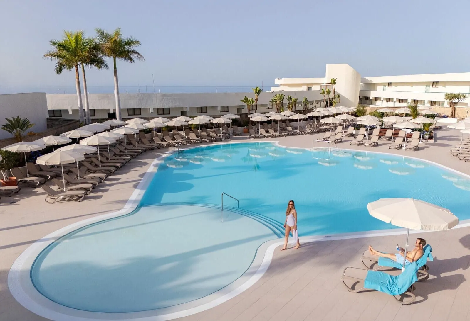 AluaSoul Costa Adeje: A pool area with lounge chairs and umbrellas, a clear sky