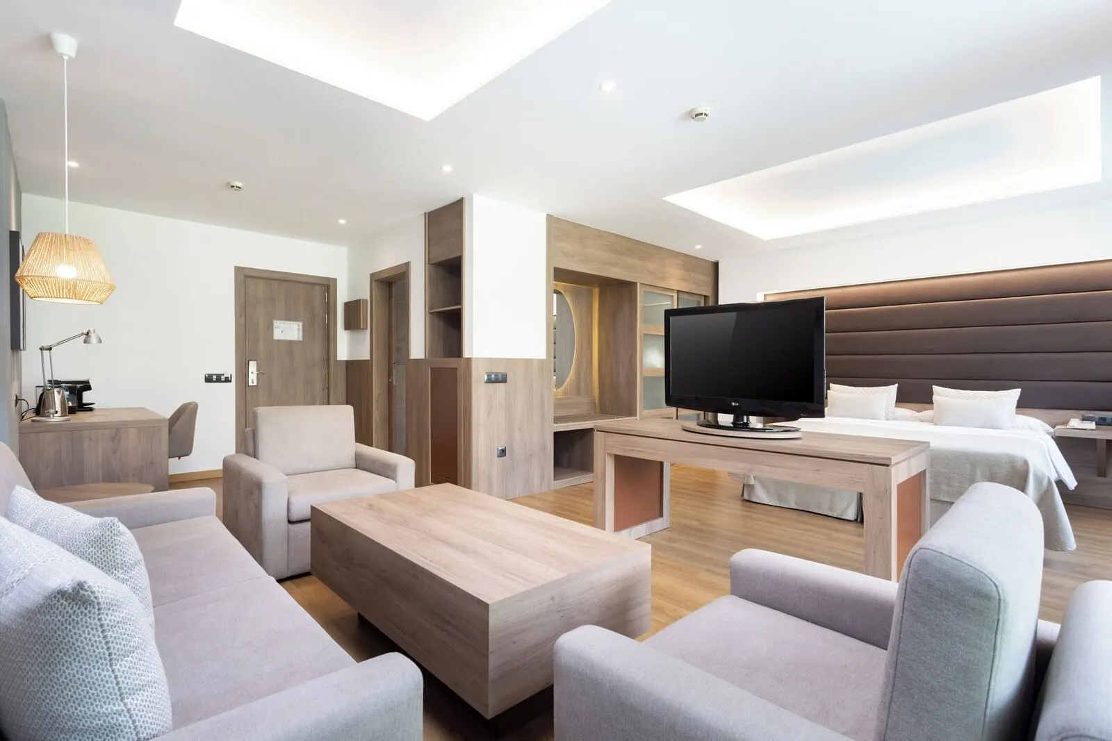 Hotel Colón Rambla: A modern hotel room with a flat-screen TV, a sofa, a coffee table, and a bed
