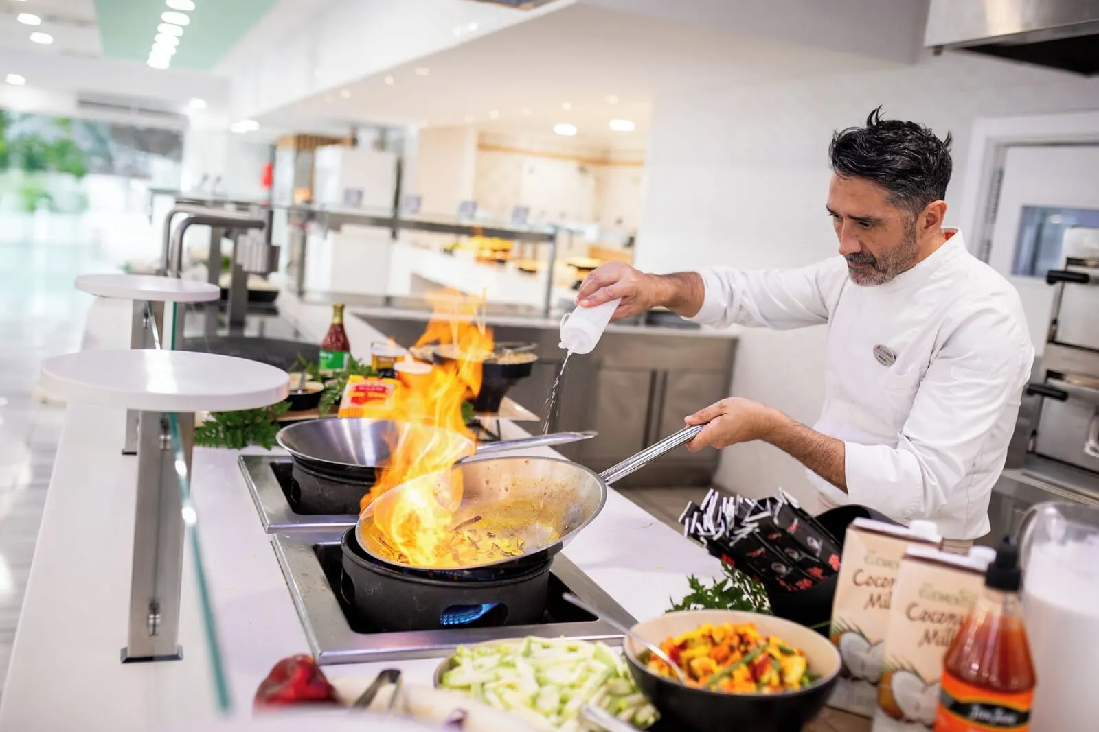 Alexandre Troya: A chef cooking with a pan on a stove, surrounded by kitchen equipment and ingredients