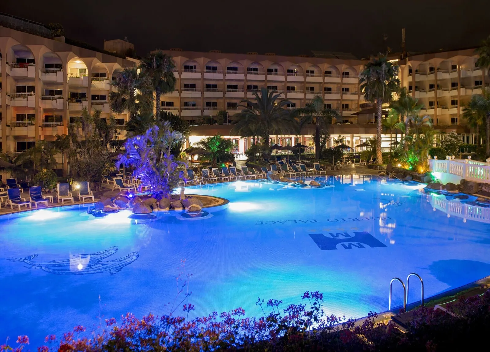 Hotel Puerto Palace: A hotel pool area with lounge chairs, palm trees