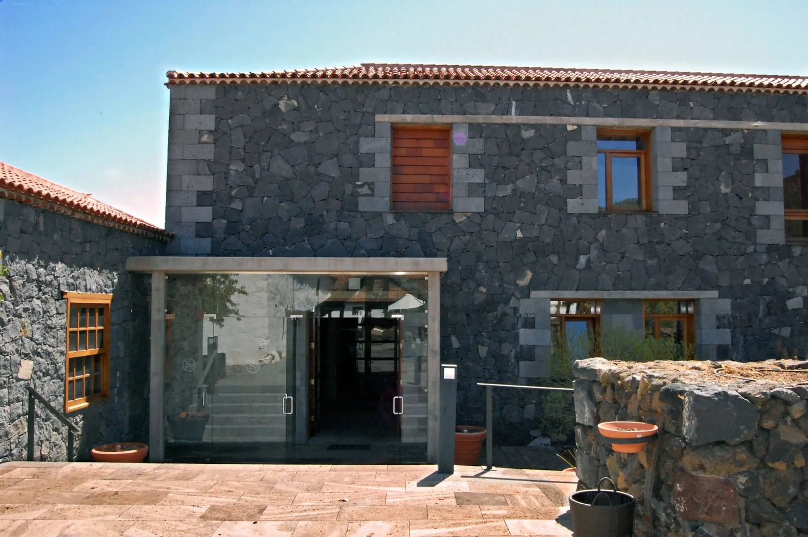 Hotel La Casona del Patio: A stone building with a tiled roof, a glass entrance, and a small window