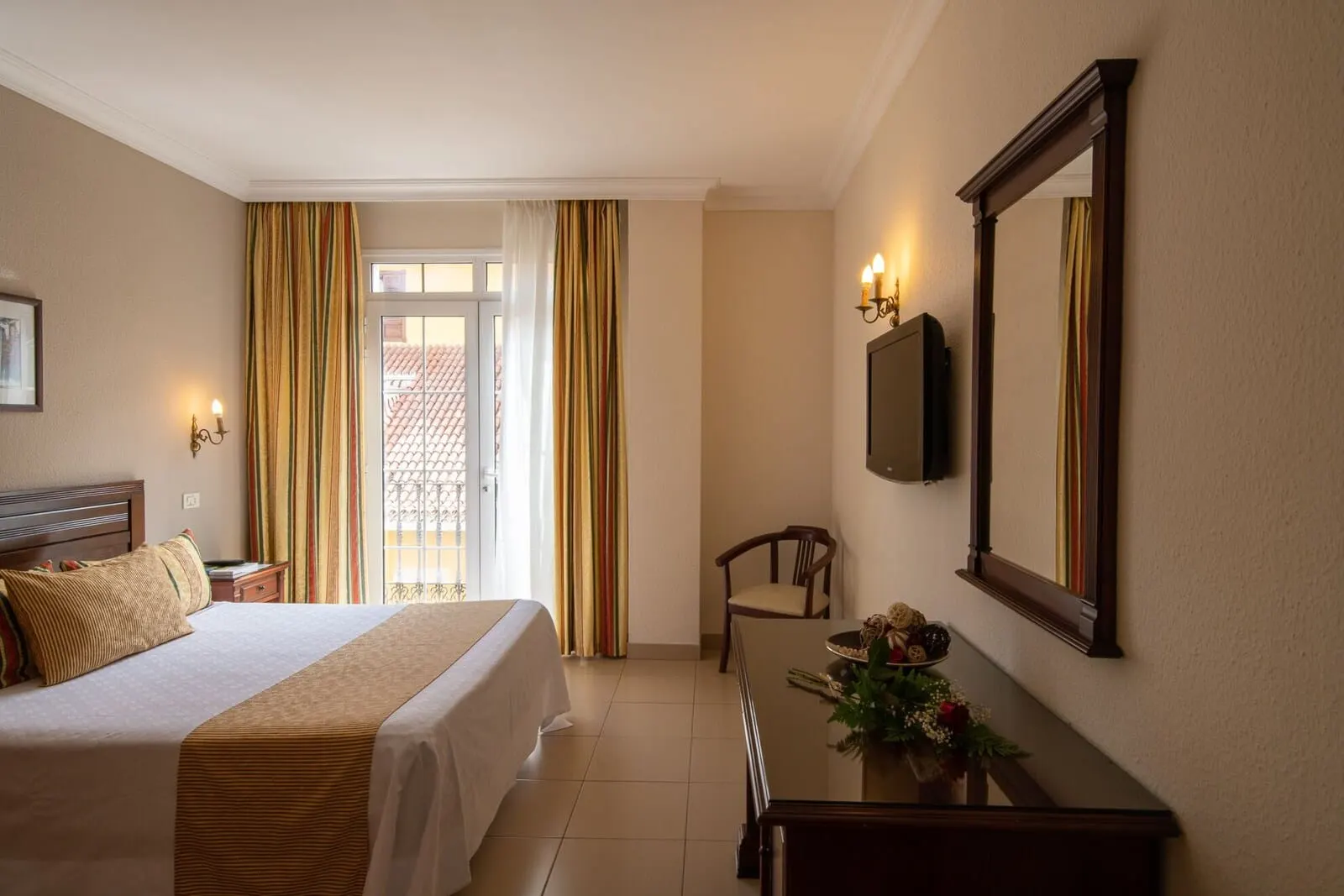 Hotel Marte: A hotel room with a bed, a desk, a chair, a mirror, and a window with curtains