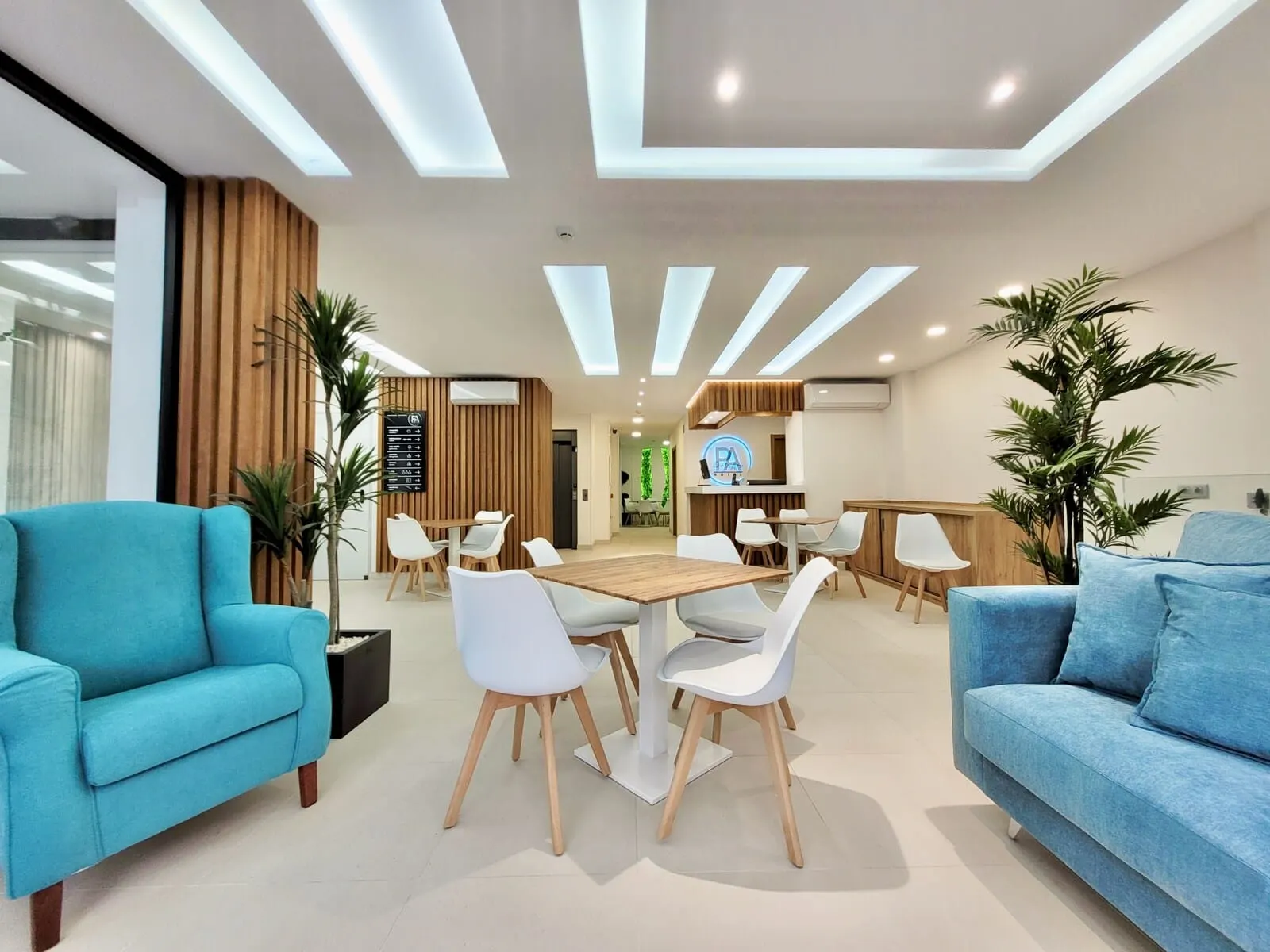 Hotel Puerto Azul: A modern hotel lobby with a central wooden table, white chairs, and blue sofas