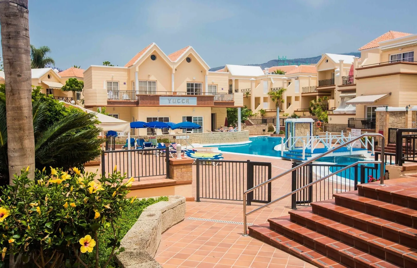 Yucca Park Aparthotel: A hotel with a swimming pool, outdoor seating, and a staircase leading to the pool area