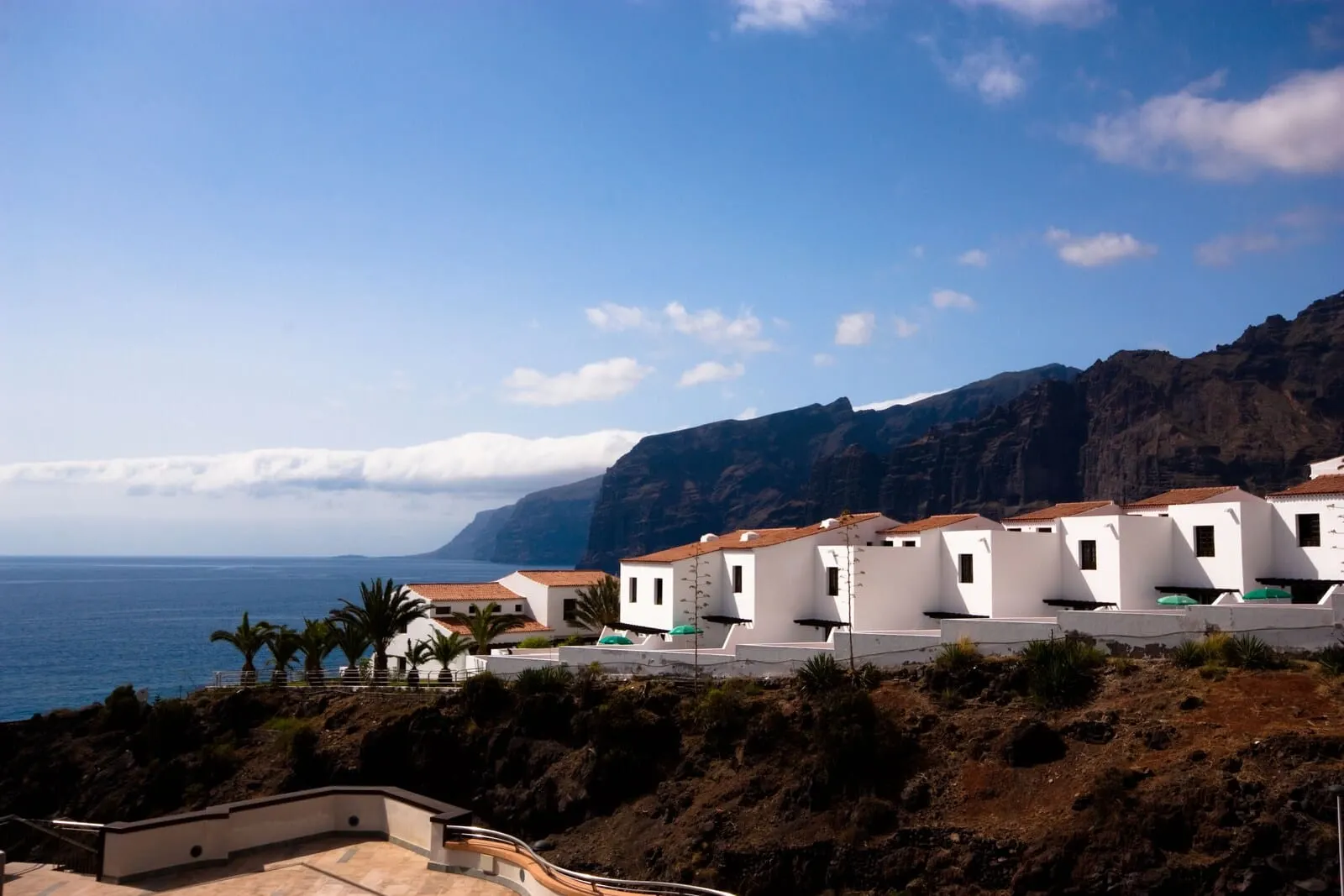 Vigilia Park: A coastal village with white buildings, a rocky cliff, and the sea in the background