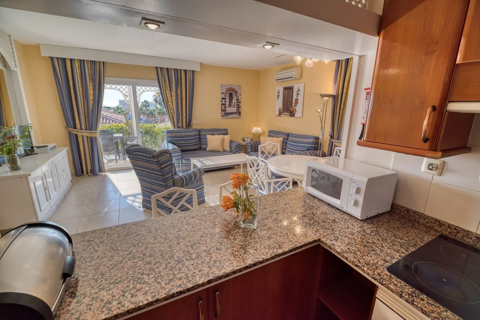 Ona Sueño Azul: A modern kitchen with granite countertops, a microwave, and a built-in stove
