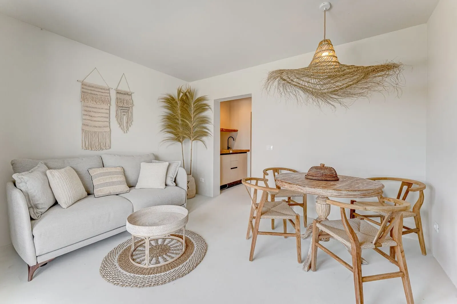 Costa Mágica Boutique Hotel: A modern living room with a grey sofa, wooden dining table, and woven light fixture