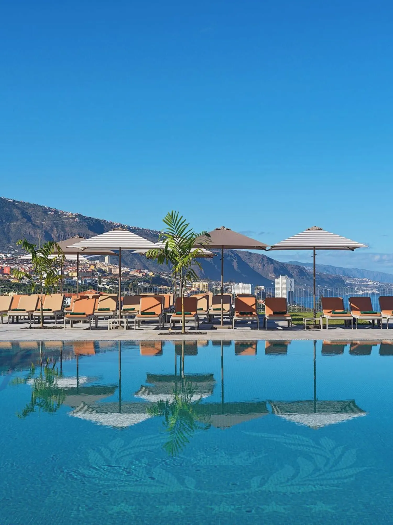Gran Hotel Taoro: A poolside area with lounge chairs and umbrellas, a clear blue sky