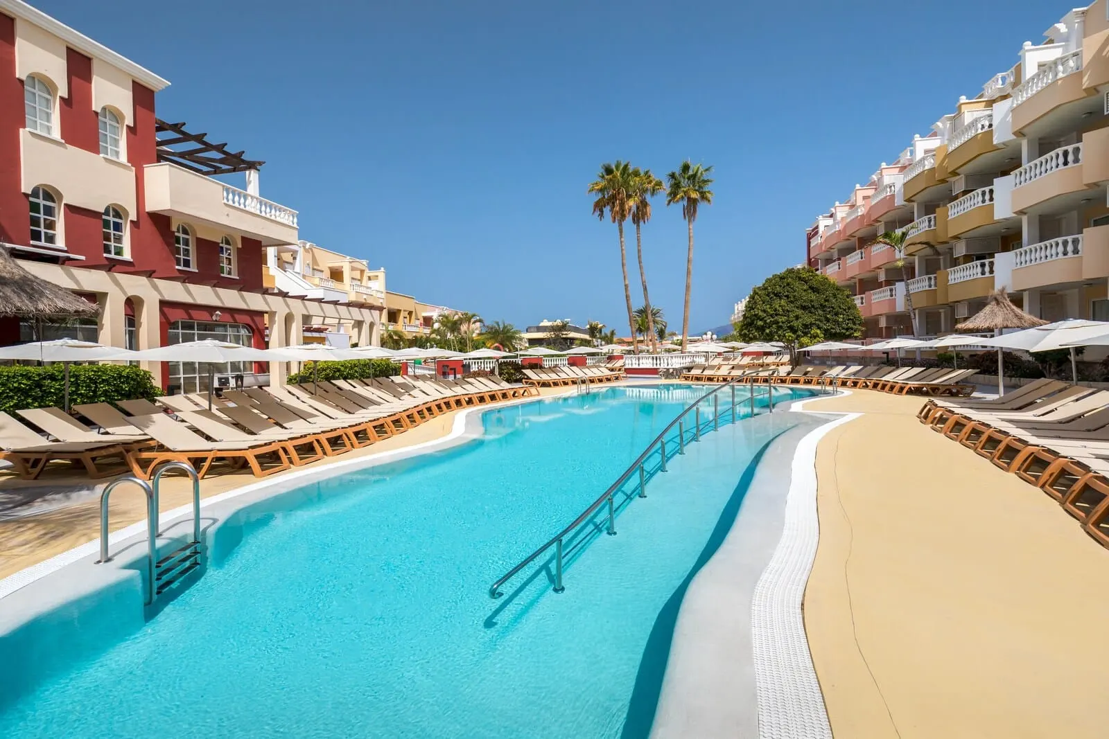 Servatur Isora Suites: A resort pool with sun loungers and a palm tree