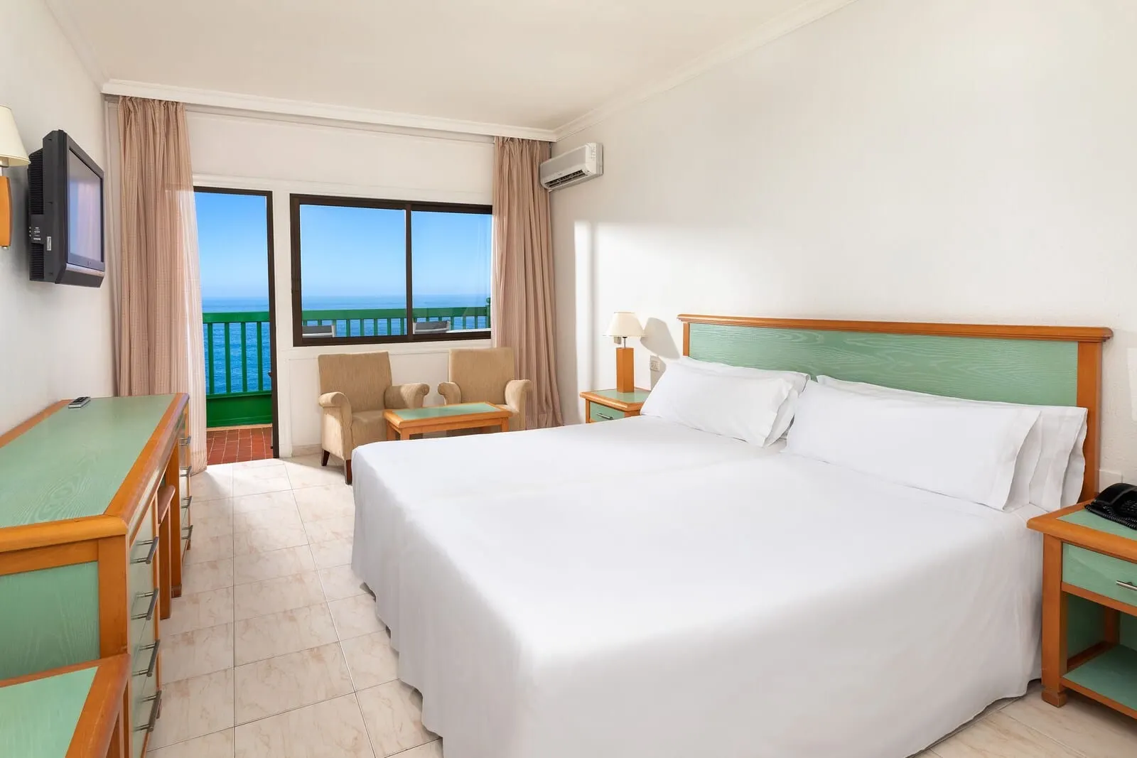 Sol Puerto de la Cruz Tenerife: A hotel room with a large bed, a desk, a chair, and a view of the sea