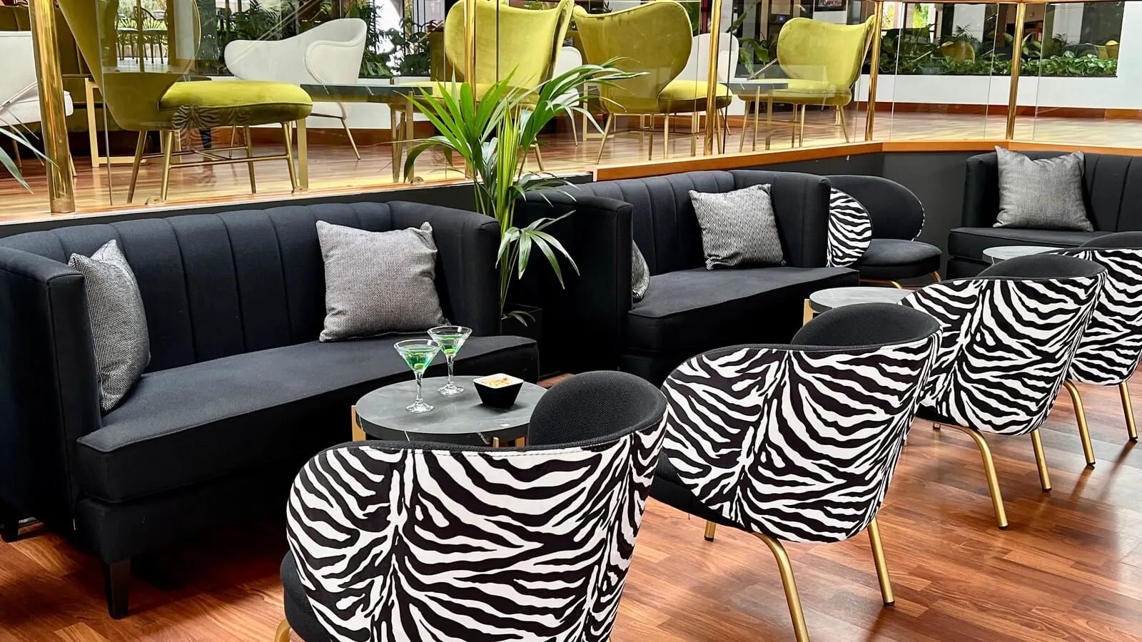 Hotel Puerto Palace: A modern lounge area with a black sectional sofa, zebra-patterned chairs