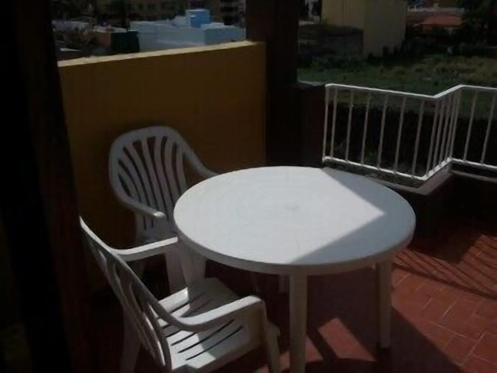 Hotel Tejuma: A small outdoor patio with a round white table and two white plastic chairs