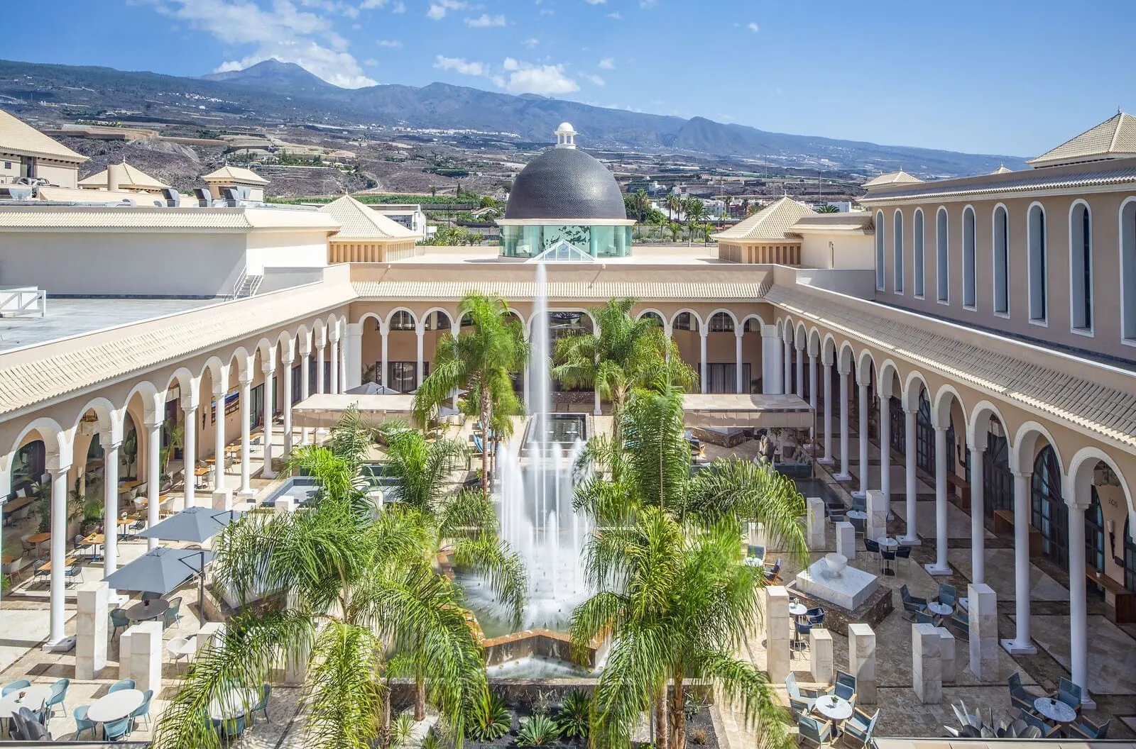 Gran Meliá Palacio de Isora: A courtyard with a central fountain, surrounded by palm trees and outdoor seating