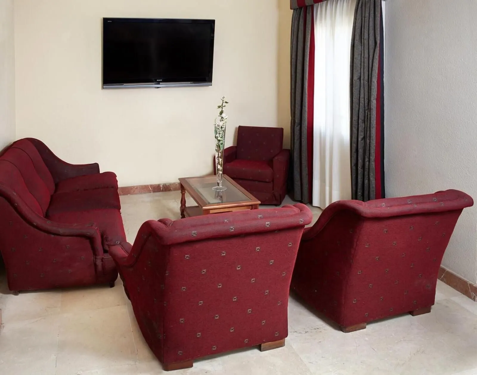 Hotel Tanausú: A living room with a flat-screen TV, red upholstered furniture, a glass coffee table