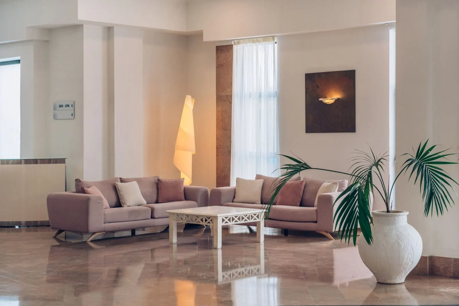 Iberostar Waves Las Dalias: A modern lobby with a sectional sofa, a coffee table, and a large potted plant