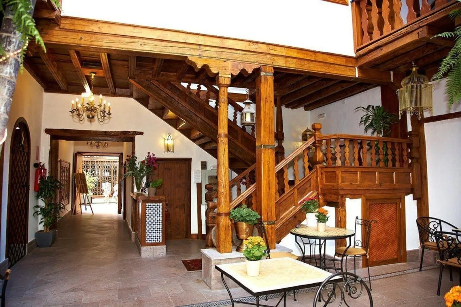 Hotel Emblemático San Agustín: A wooden staircase with a railing, a chandelier, and potted plants