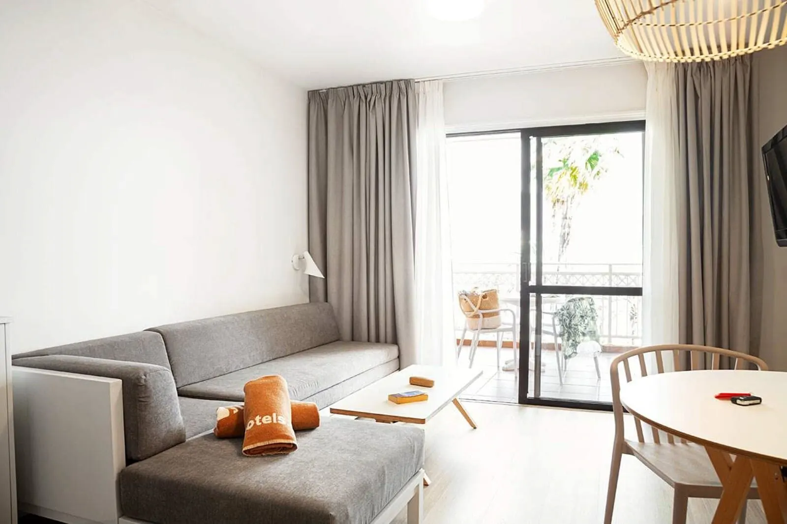 Coral Compostela Beach: A modern living room with a grey sofa, a small table, and a dining area with a chair