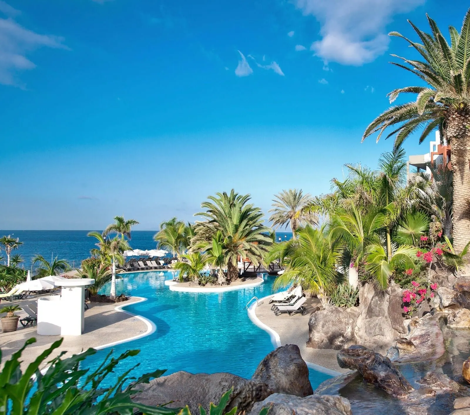 Roca Nivaria Gran Hotel: A resort pool with a view of the ocean, surrounded by palm trees and lounge chairs