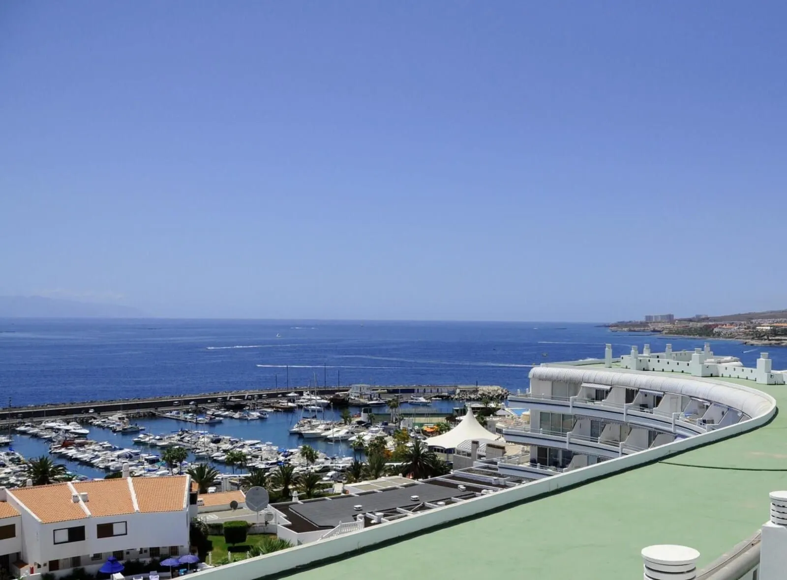 HOVIMA Atlantis: A marina with boats, a curved building with a green roof, and a clear blue sky