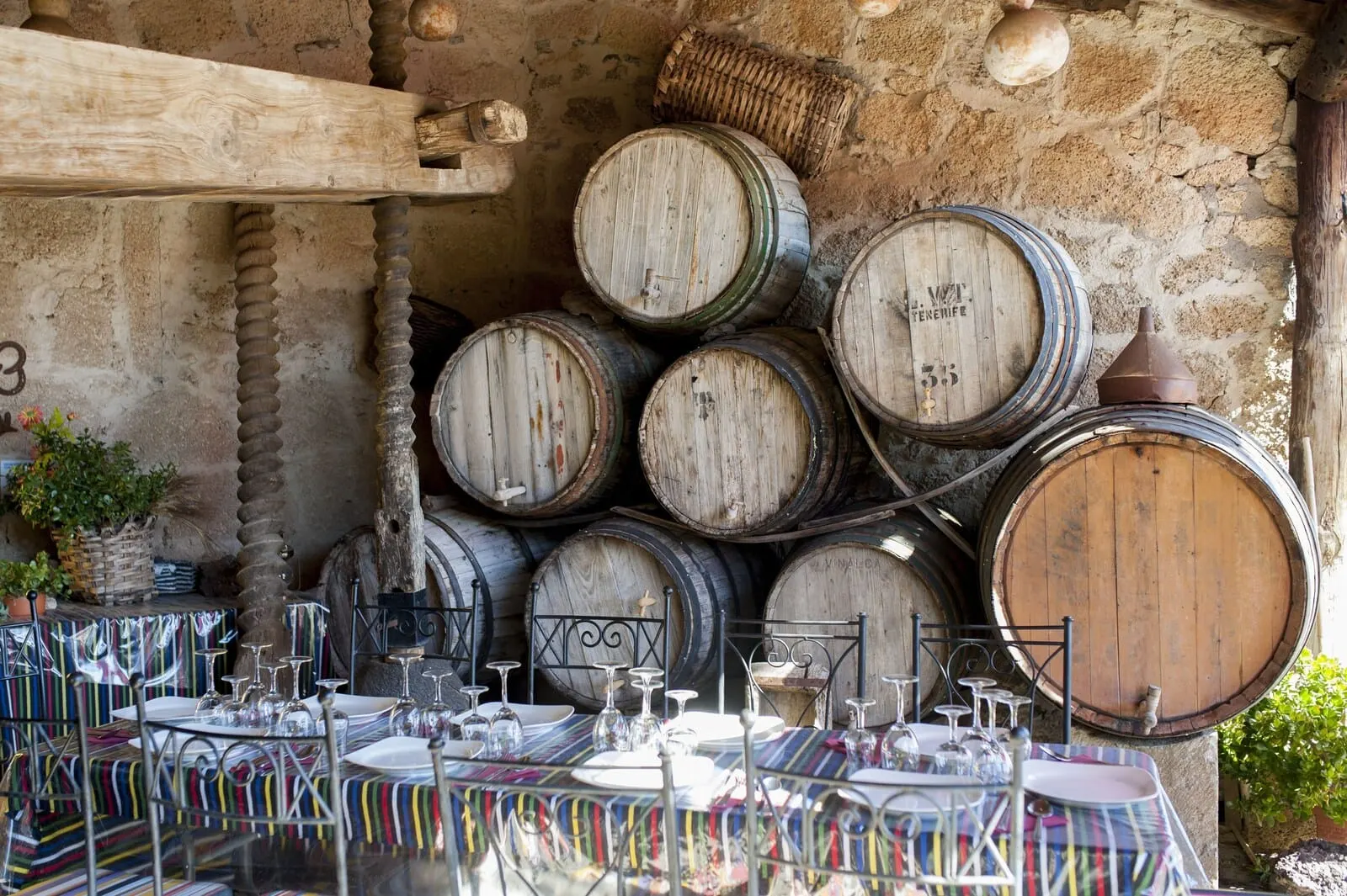 Hotel Rural Senderos de Abona: A rustic outdoor dining area with wooden barrels stacked against a stone wall