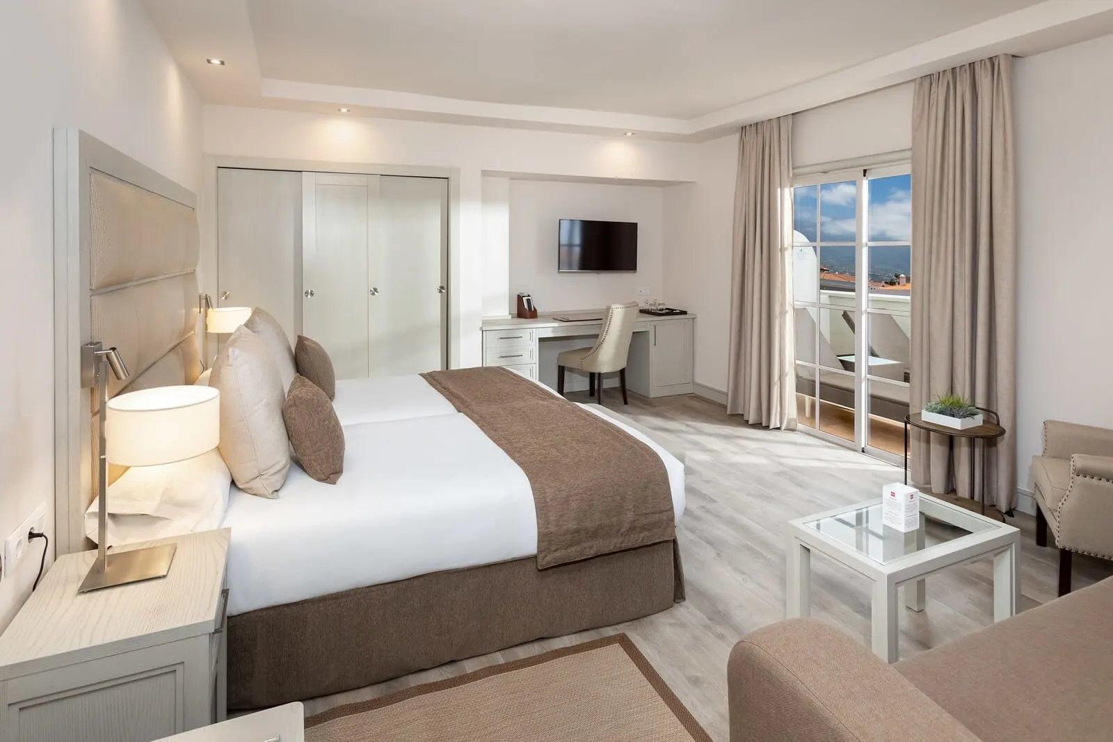 Hotel Riu Garoé: A hotel room with a bed, desk, TV, and a balcony with a view