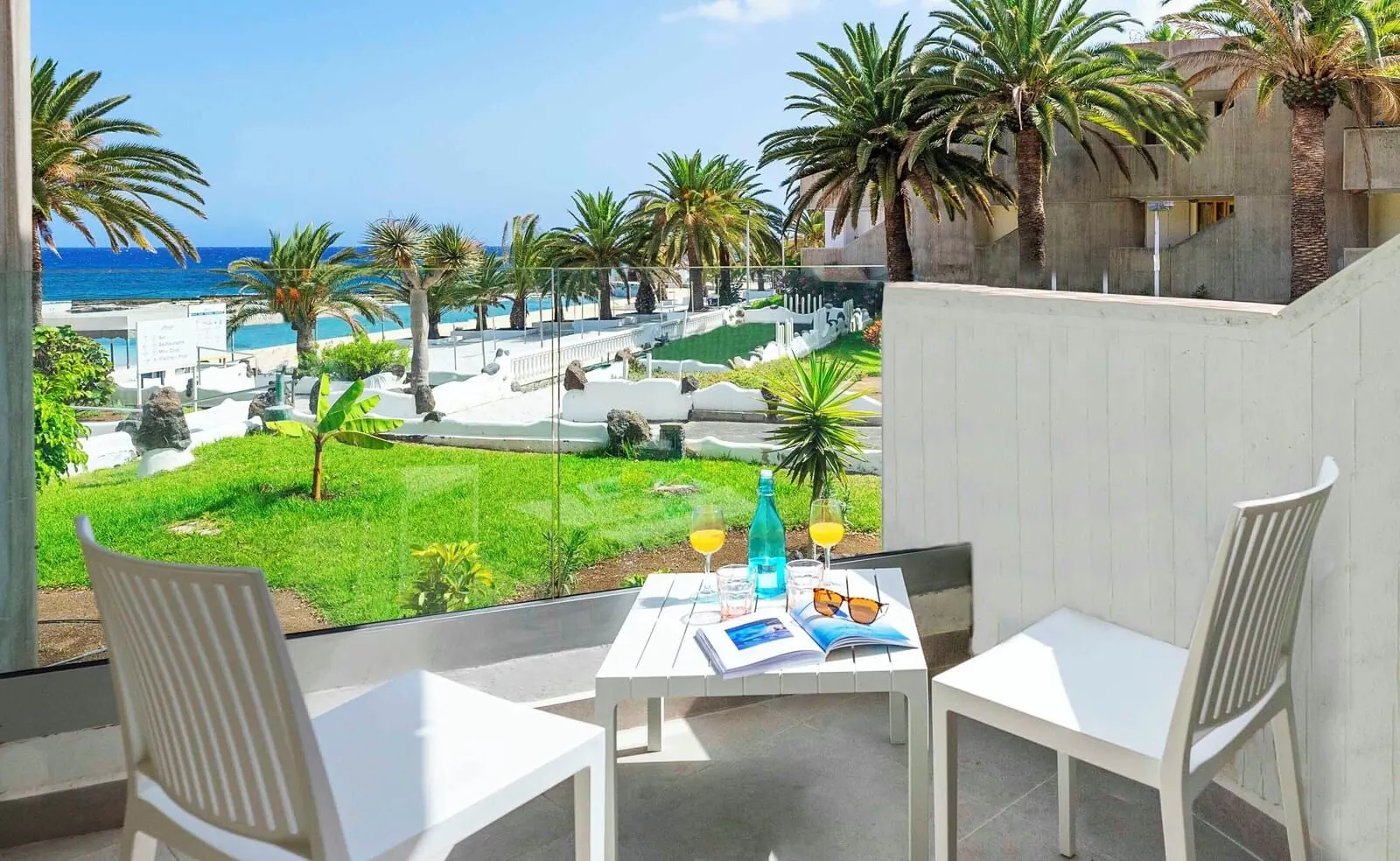 Ona Alborada: A balcony with white chairs, a table with drinks and a magazine