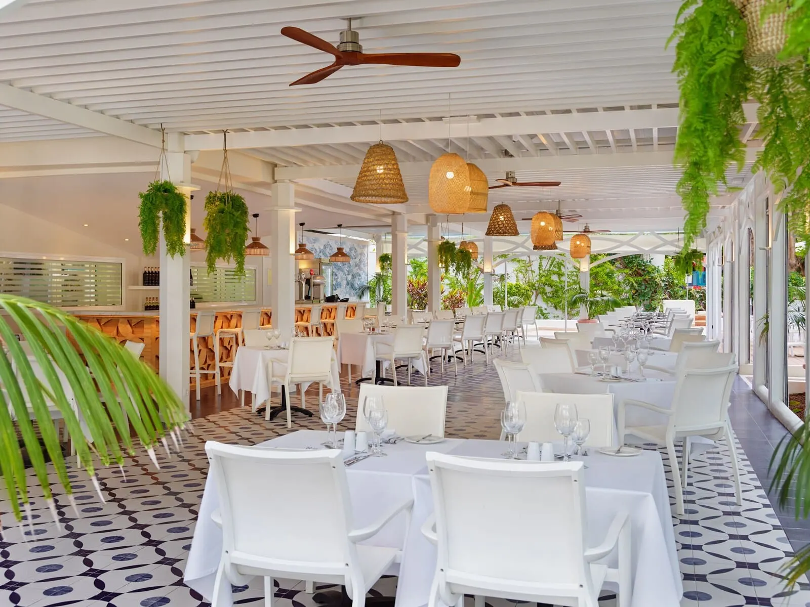 H10 Tenerife Playa: A restaurant with white tables and chairs, hanging plants, and a ceiling fan