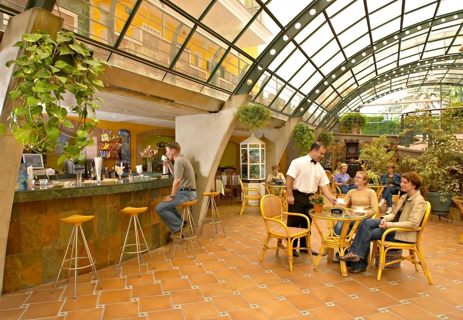 Apartamentos La Carabela: An indoor café with a high ceiling and glass panels