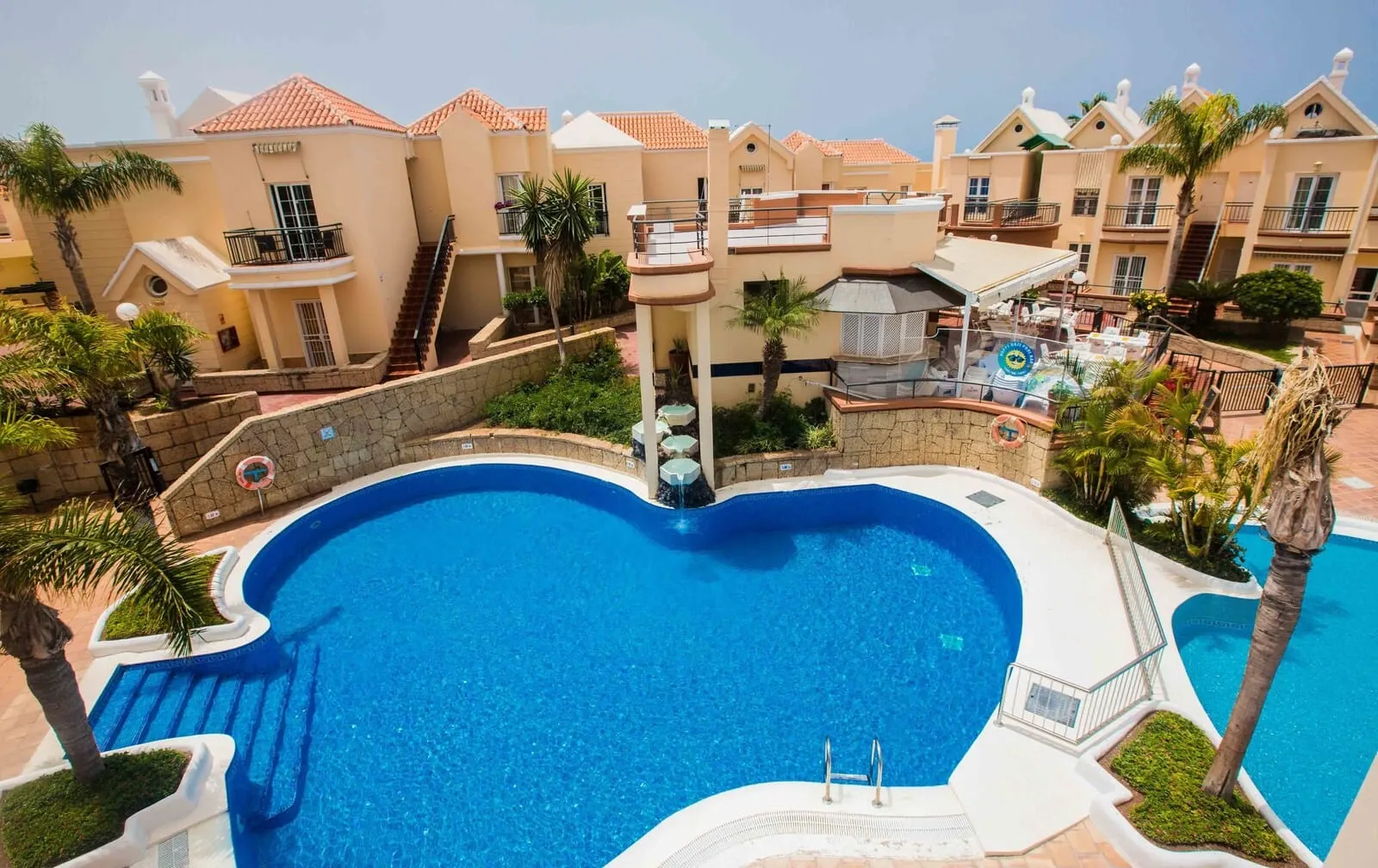 Yucca Park Aparthotel: A large swimming pool surrounded by multi-story buildings with balconies, palm trees