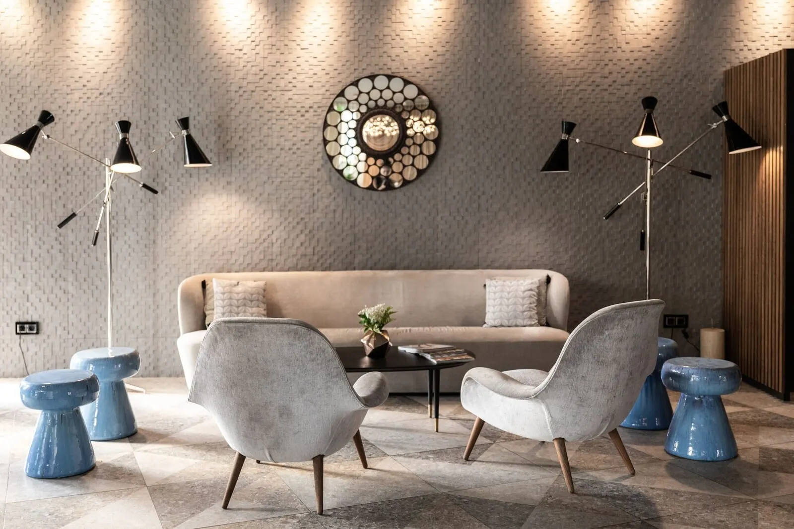 Sir Anthony: A modern living room with a beige sofa, two grey armchairs, a coffee table
