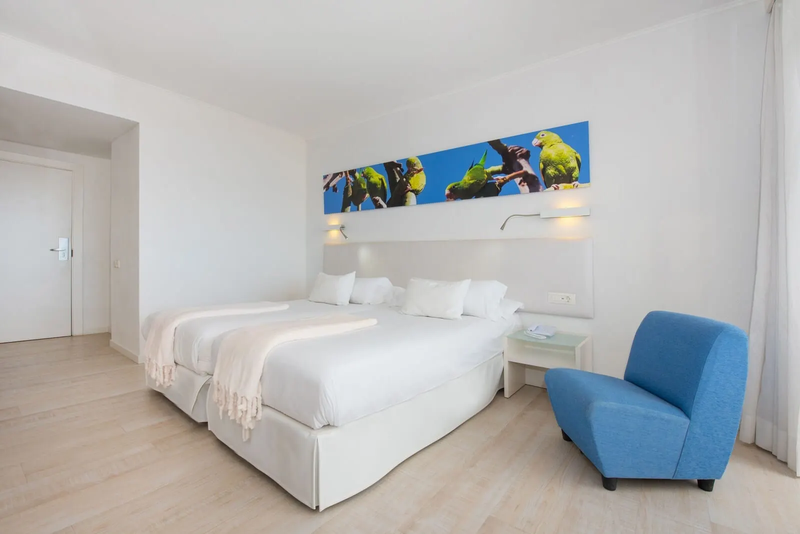 Iberostar Waves Bouganville Playa: A modern hotel room with a large bed, a blue armchair