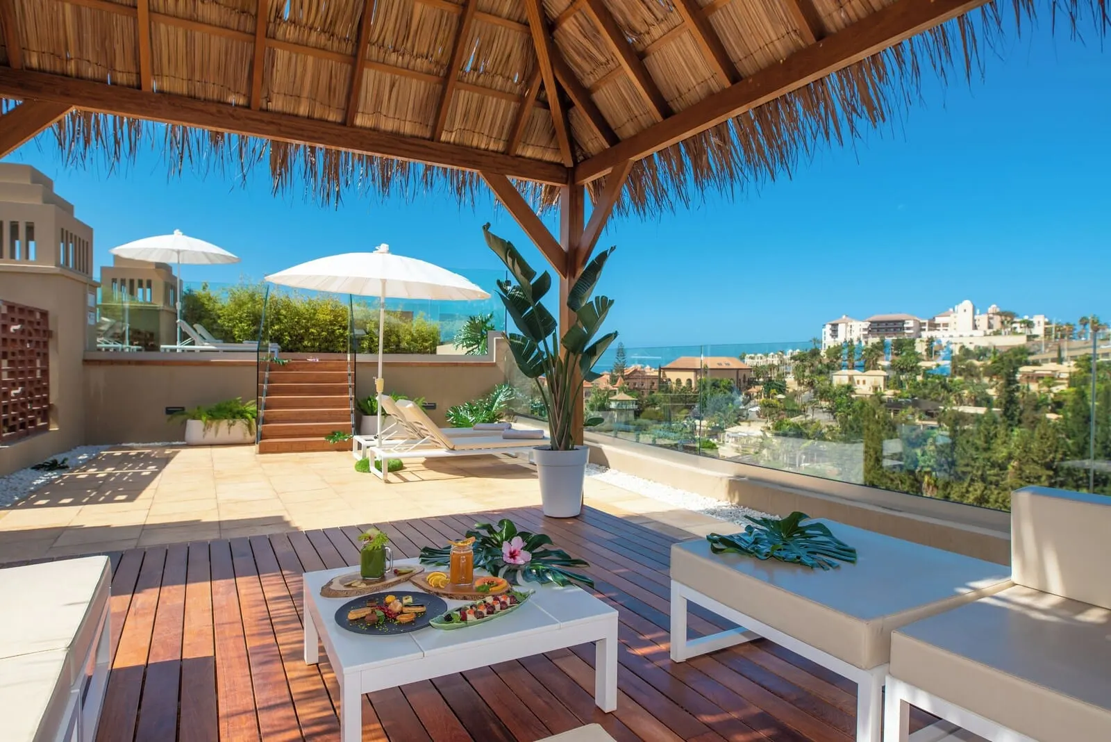 GF Victoria: A wooden deck with a thatched roof, white furniture