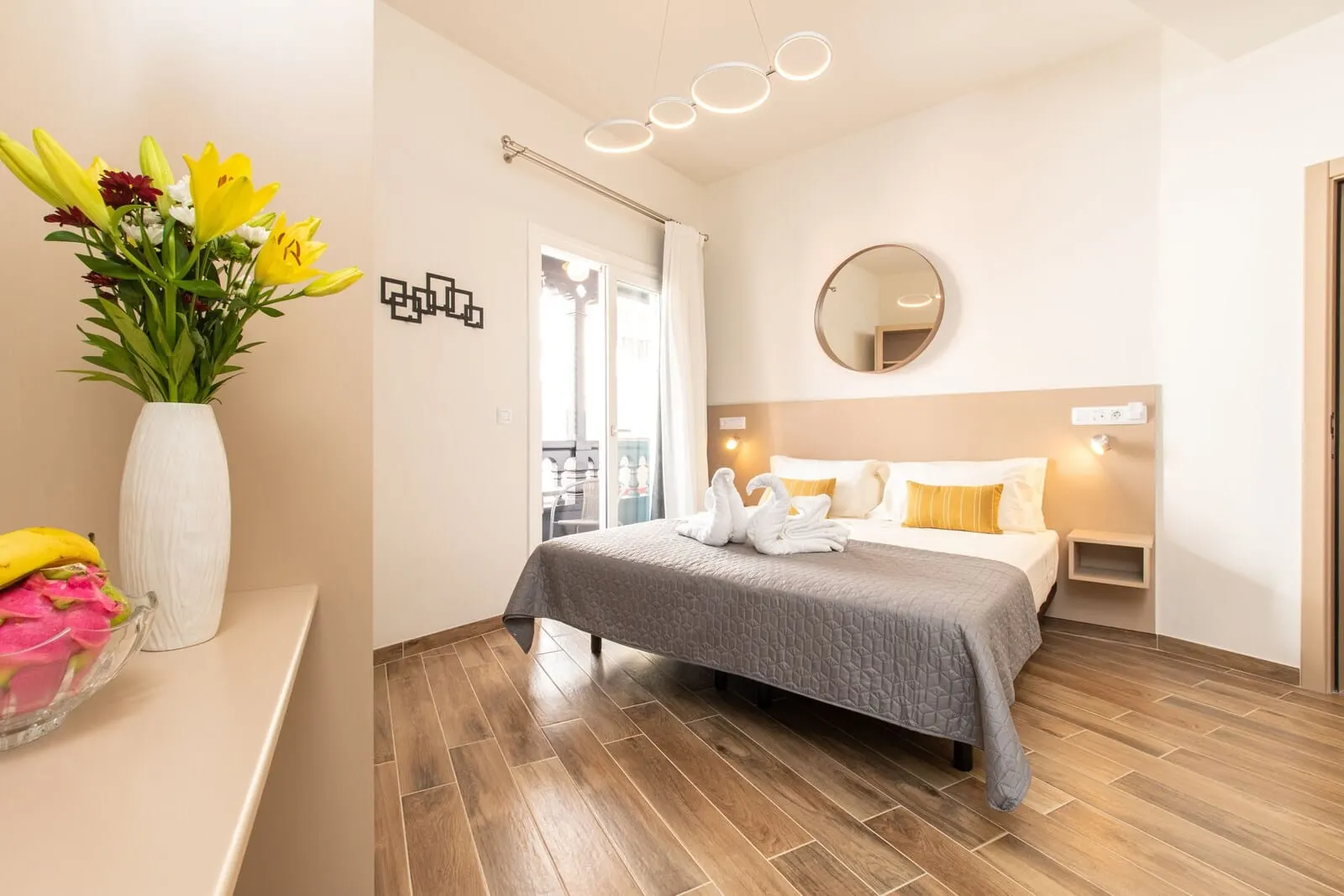 Suncanarias Hotel Adeje Plaza: A modern hotel room with a bed, a bedside table, a mirror, and a vase of flowers