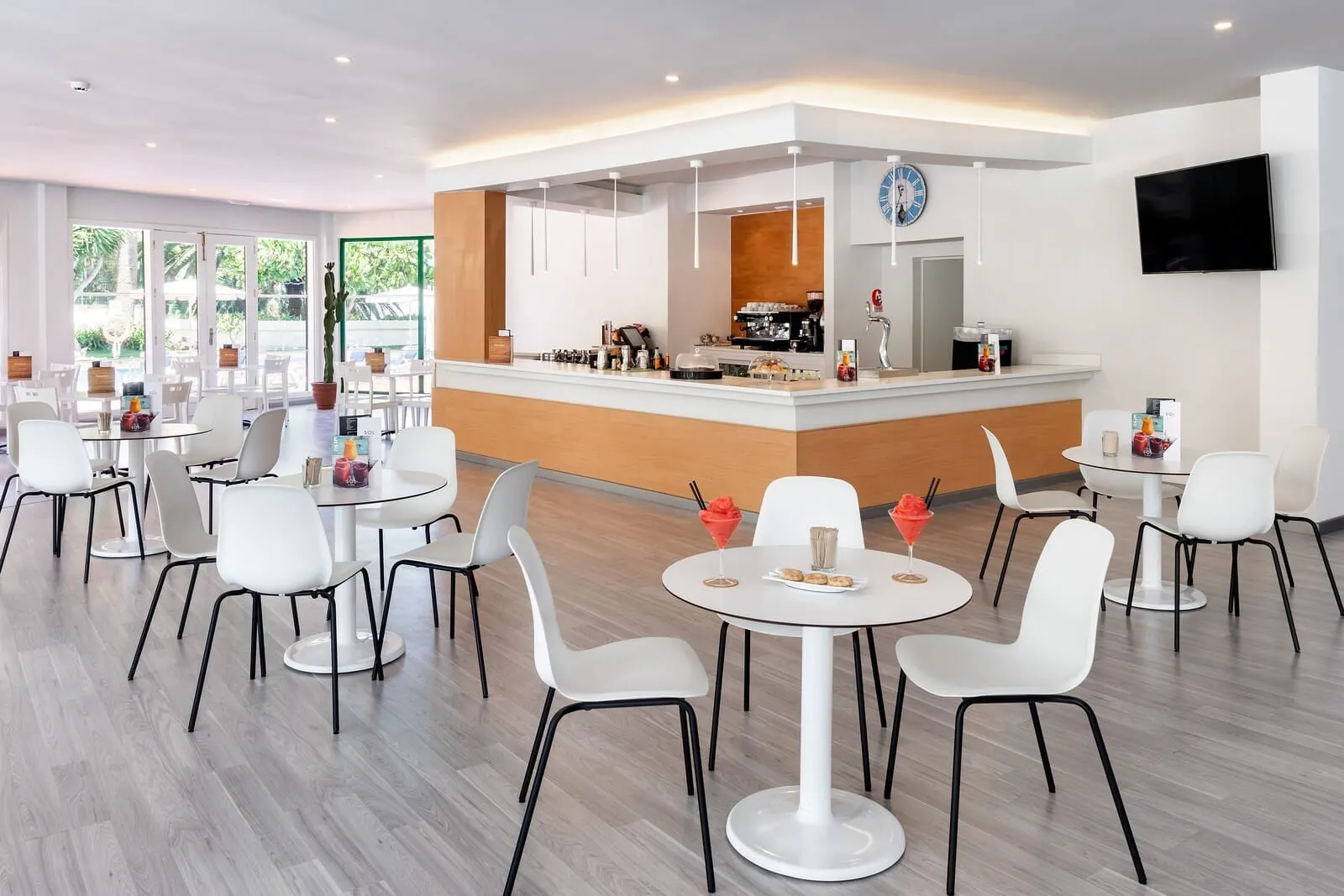 Sol Puerto de la Cruz Tenerife: A modern cafe with round tables and white chairs, a counter with coffee machines