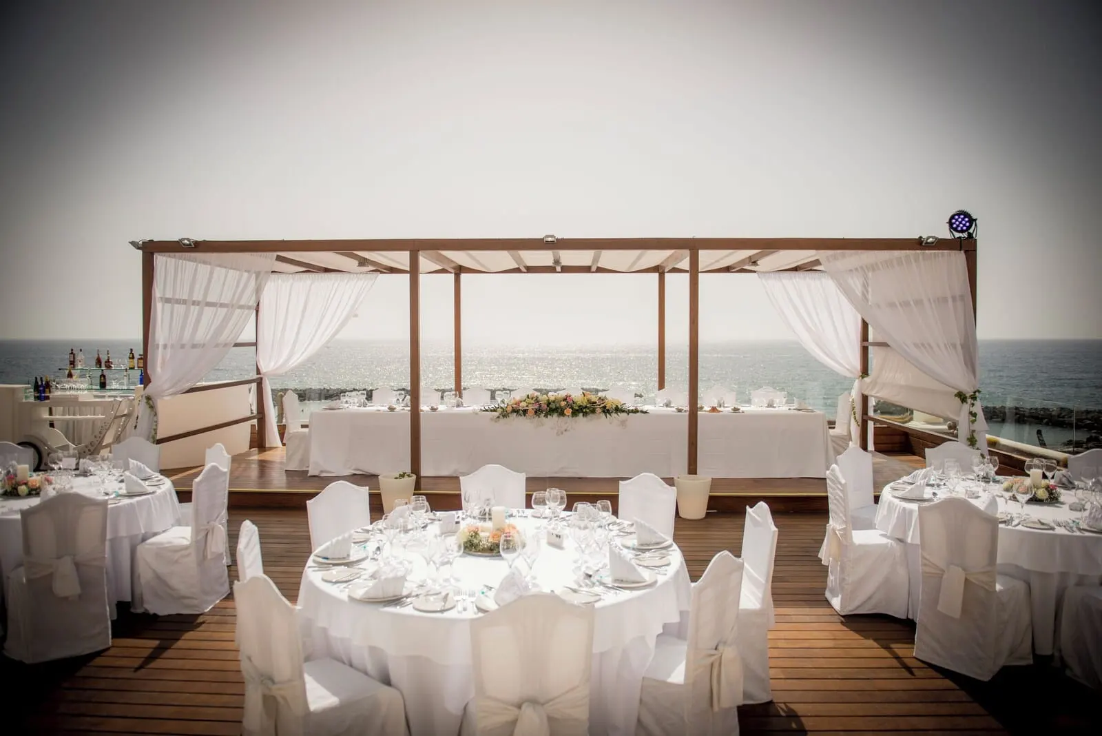 H10 Gran Tinerfe: An outdoor wedding setup with round tables and white chairs, overlooking the sea