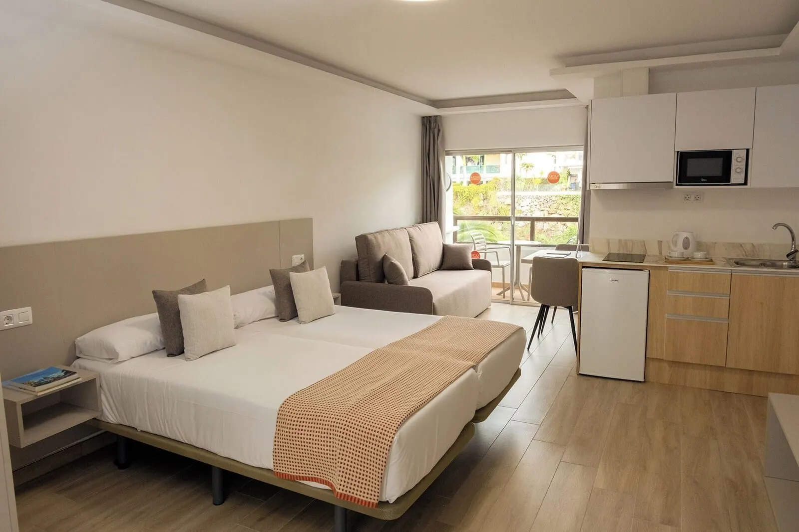 Muthu La Perla Tenerife: A modern hotel room with a bed, a sofa, a desk, and a kitchenette