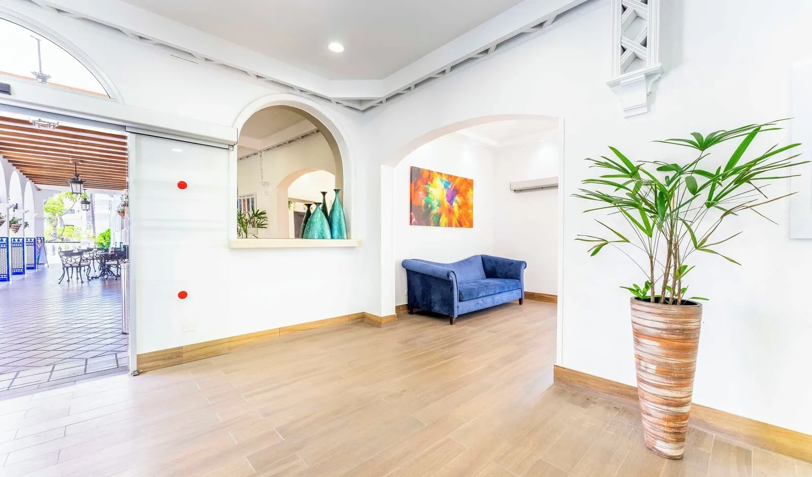 Ona Beverly Hills Heights: A spacious room with a wooden floor, a blue sofa, a large potted plant