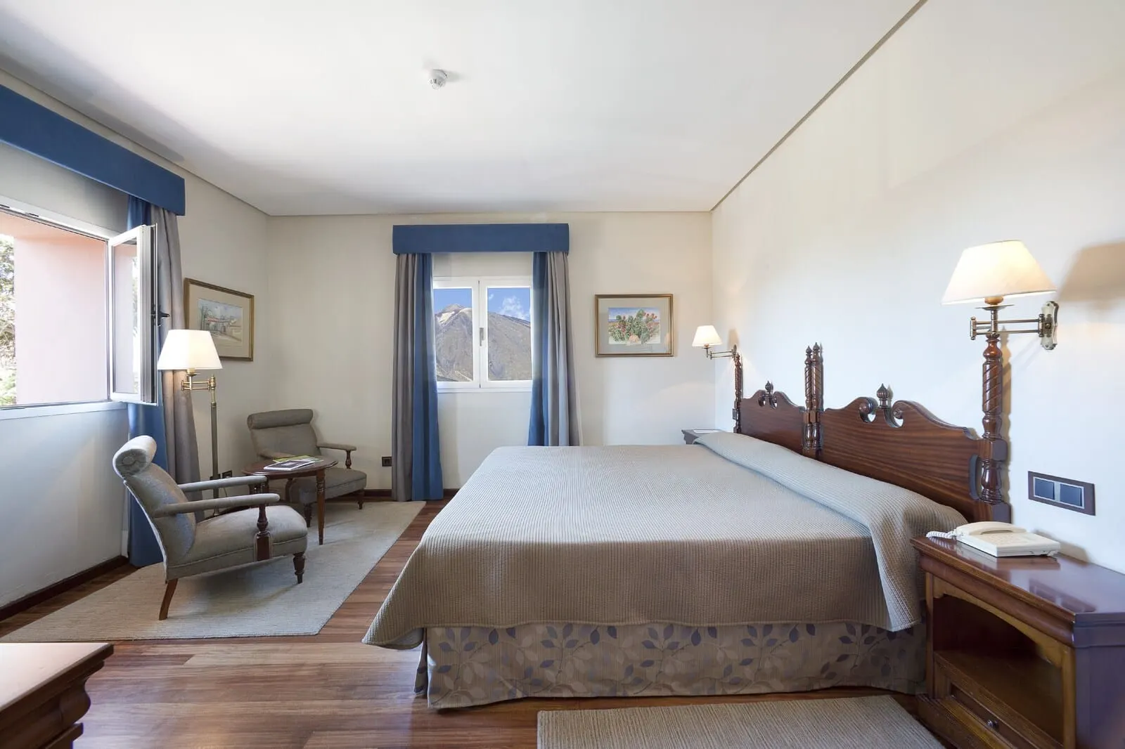 Parador de Las Cañadas del Teide: A hotel room with a large bed, a chair, a desk, and a window with curtains