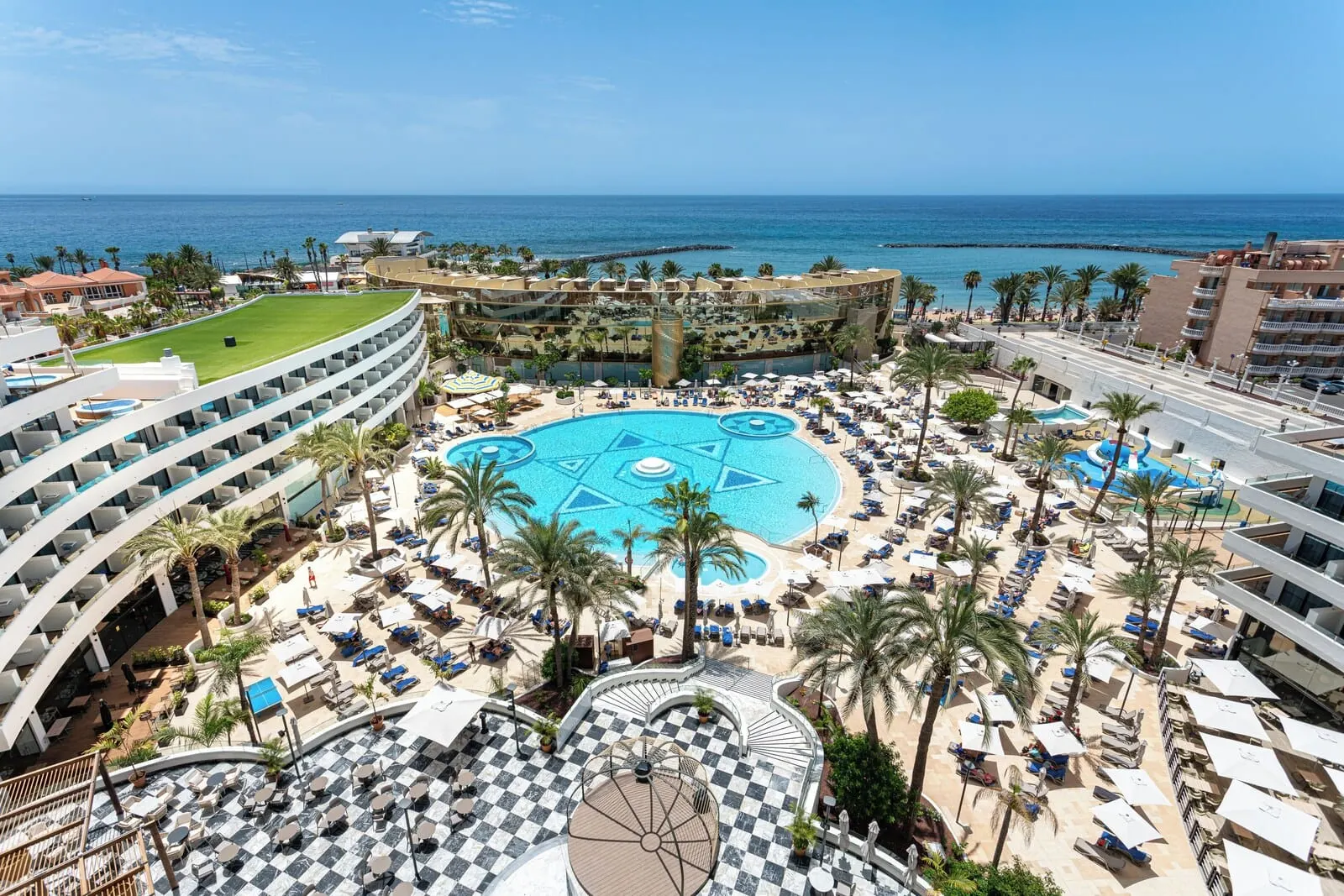 Mediterranean Palace: A resort with a central pool, multiple balconies, and a view of the ocean
